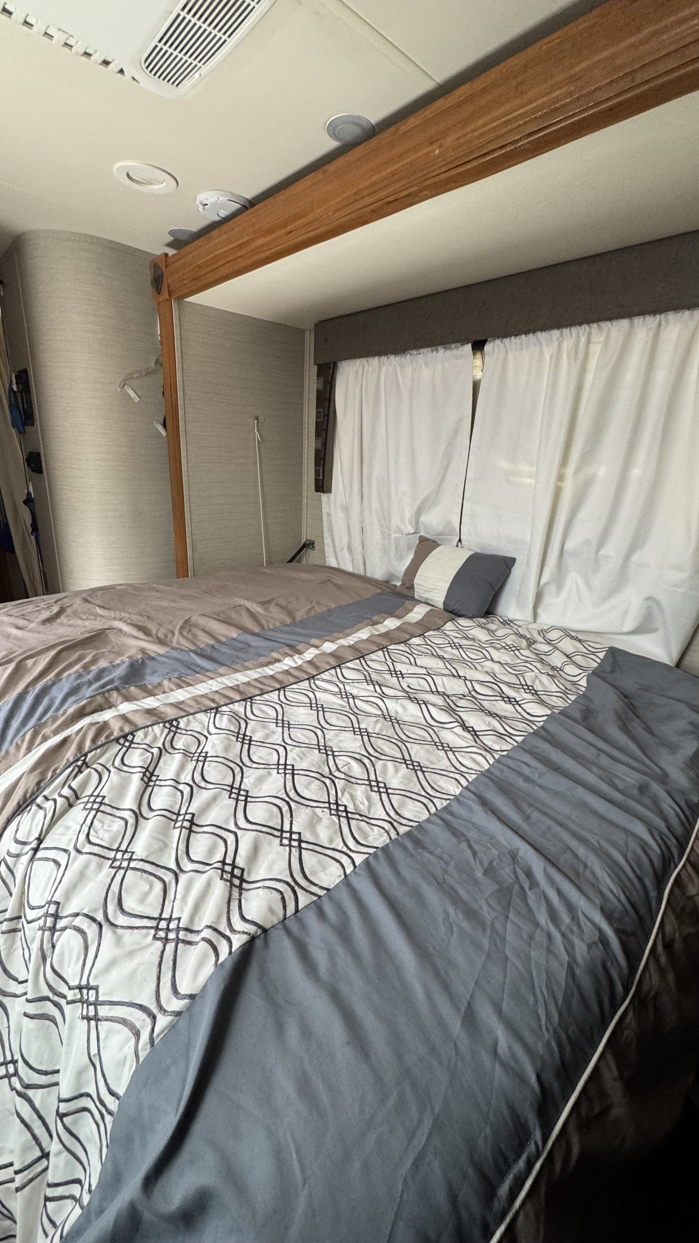 Cozy RV rental bedroom featuring a patterned bed, white window curtains, and ceiling with AC vent & lights.. Jayco Melbourne 2017
