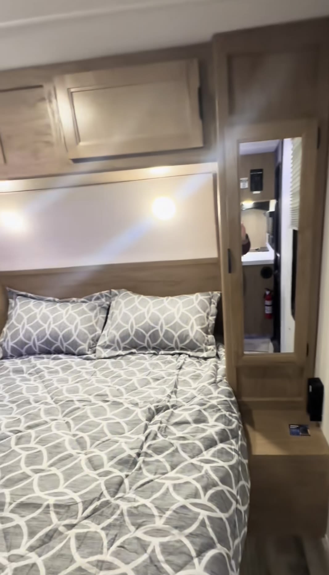RV rental bedroom: a comfortable space with a patterned bed, storage cabinets, and mirrored closet reflecting the RV interior.. Forest River Grey Wolf 26 DBH 2024
