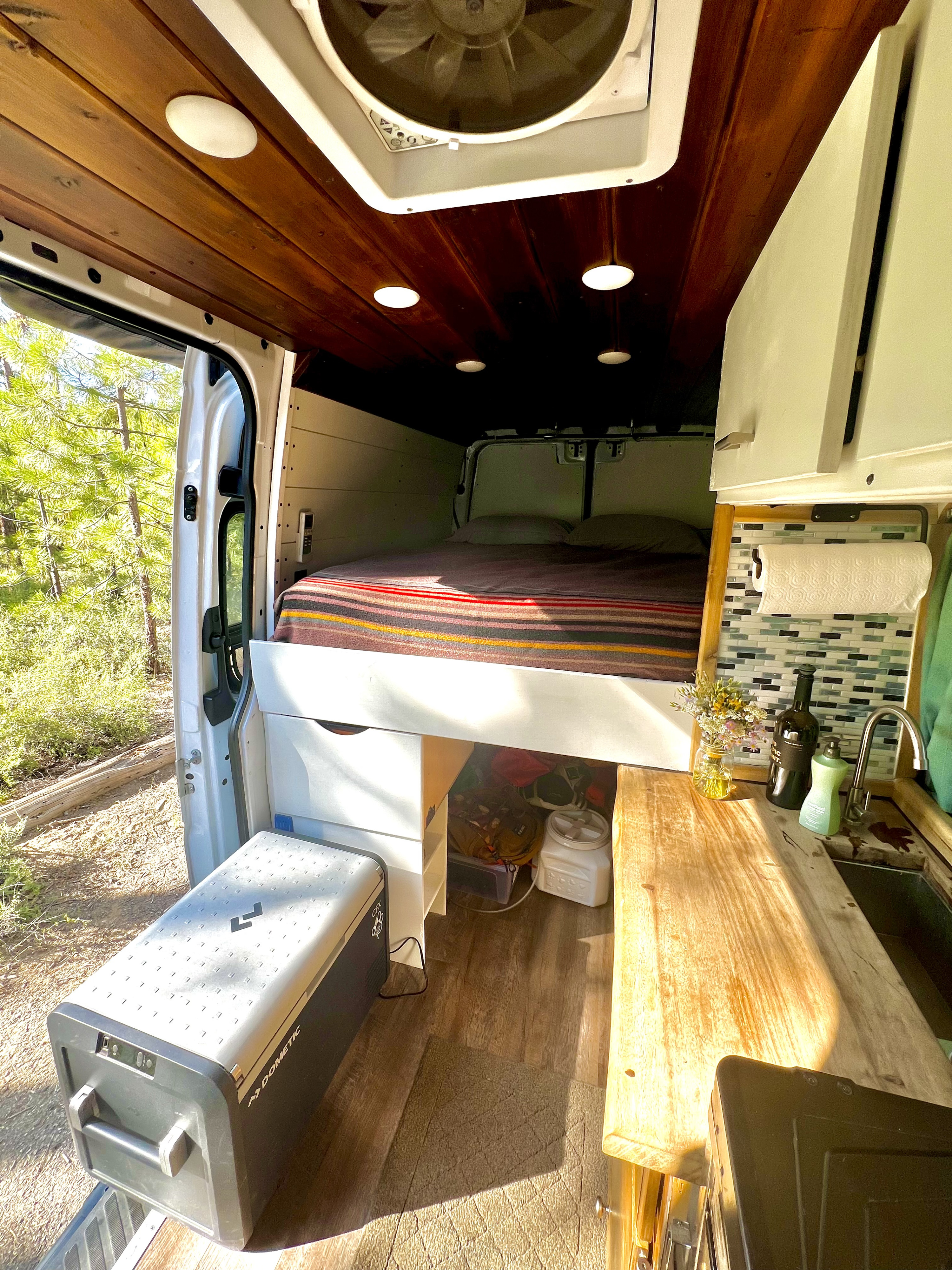 Cozy RV rental interior: bed, kitchen, Dometic cooler. Perfect for van life adventures surrounded by nature.. Mercedes-Benz Sprinter 2015