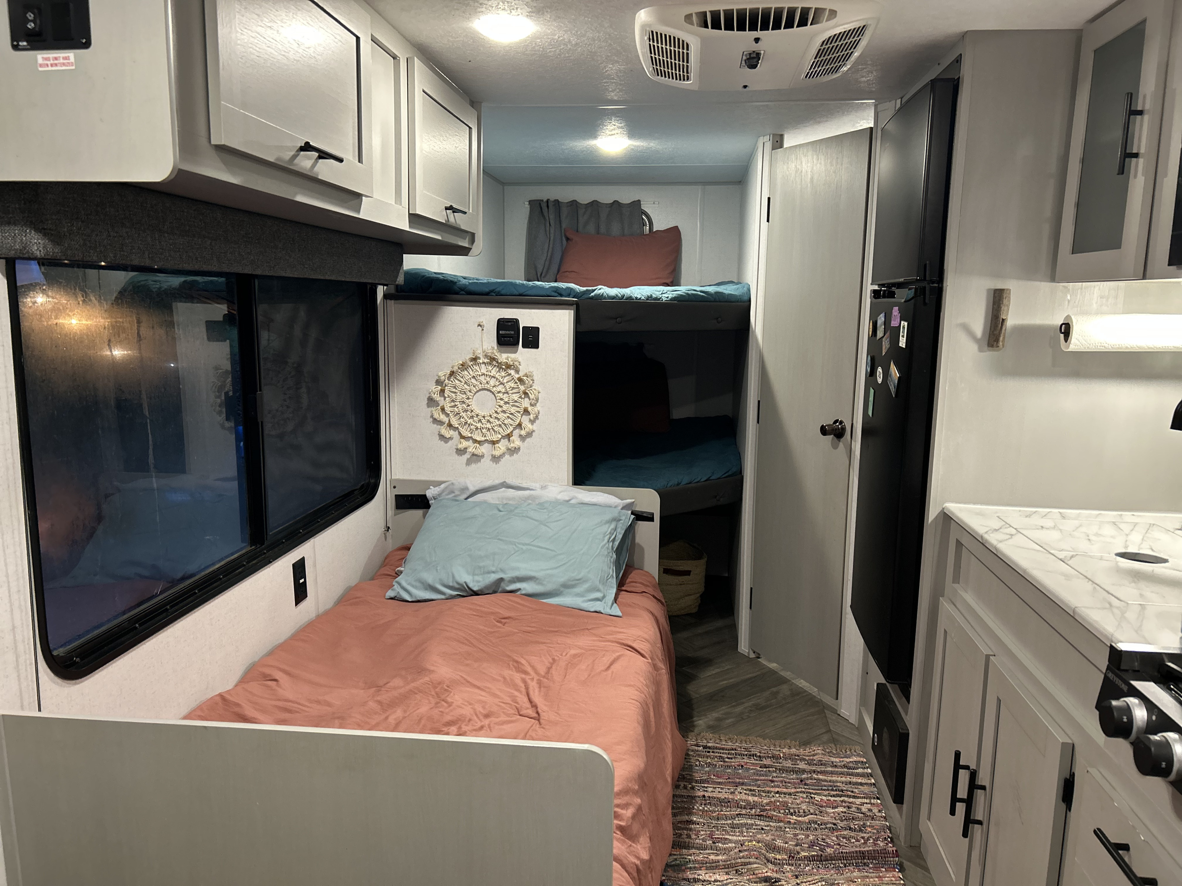 Inside an RV rental: a compact interior features a main bed, bunk beds, kitchen area with a fridge. Ready for adventure!. Forest River Wildwood FSX Platinum 2021