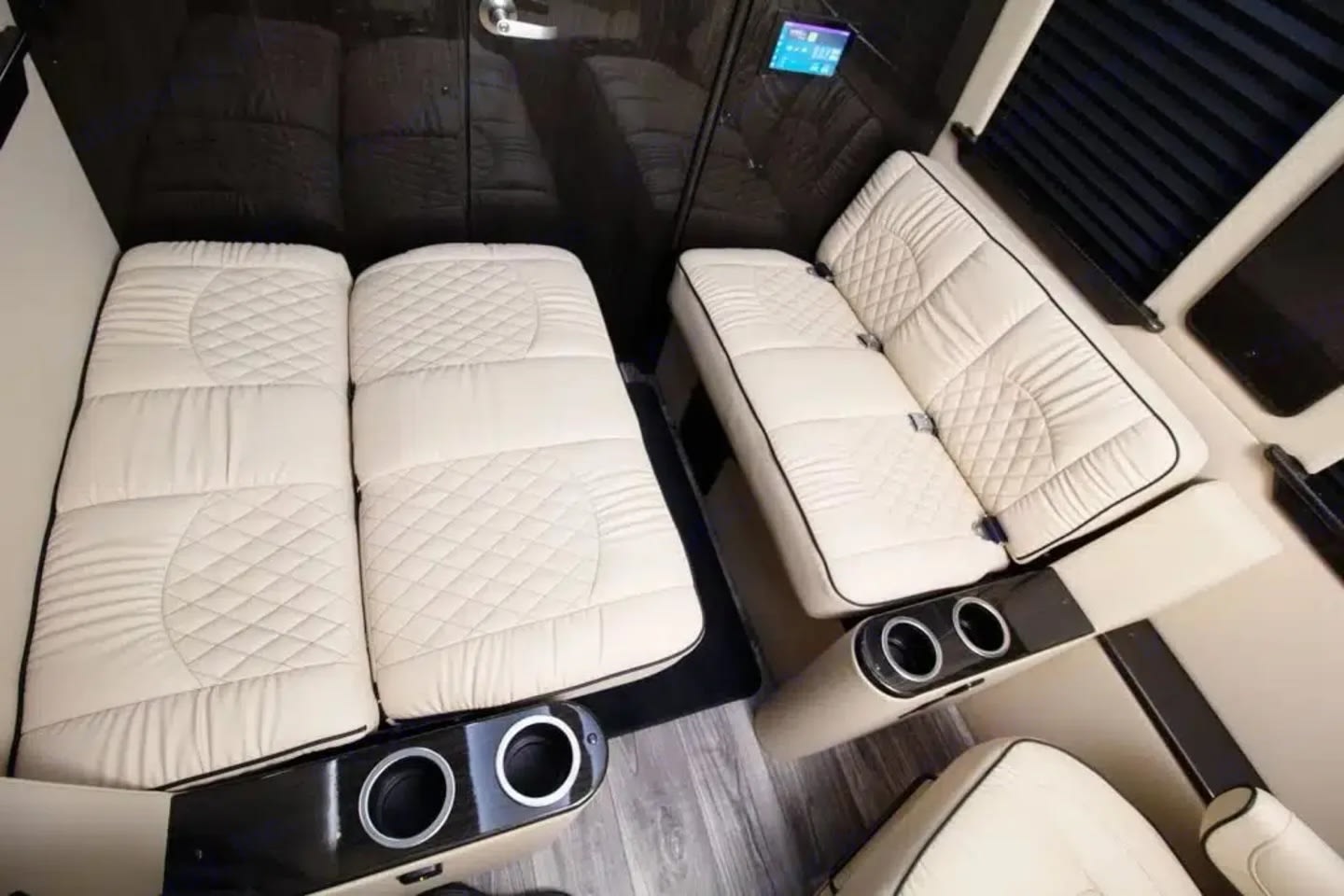 Inside a luxurious RV rental: cream quilted seating, convertible for lounge or sleep, with convenient cup holders in a premium interior.. Ultimate Toys Ultimate Cruiser 2024