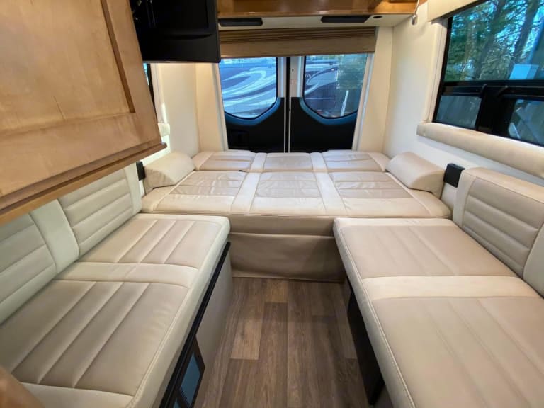 RV rental interior featuring a large convertible bed setup and two side bench seating areas in neutral tones.. Coachman Galleria 24Q Galleria 24Q 2021