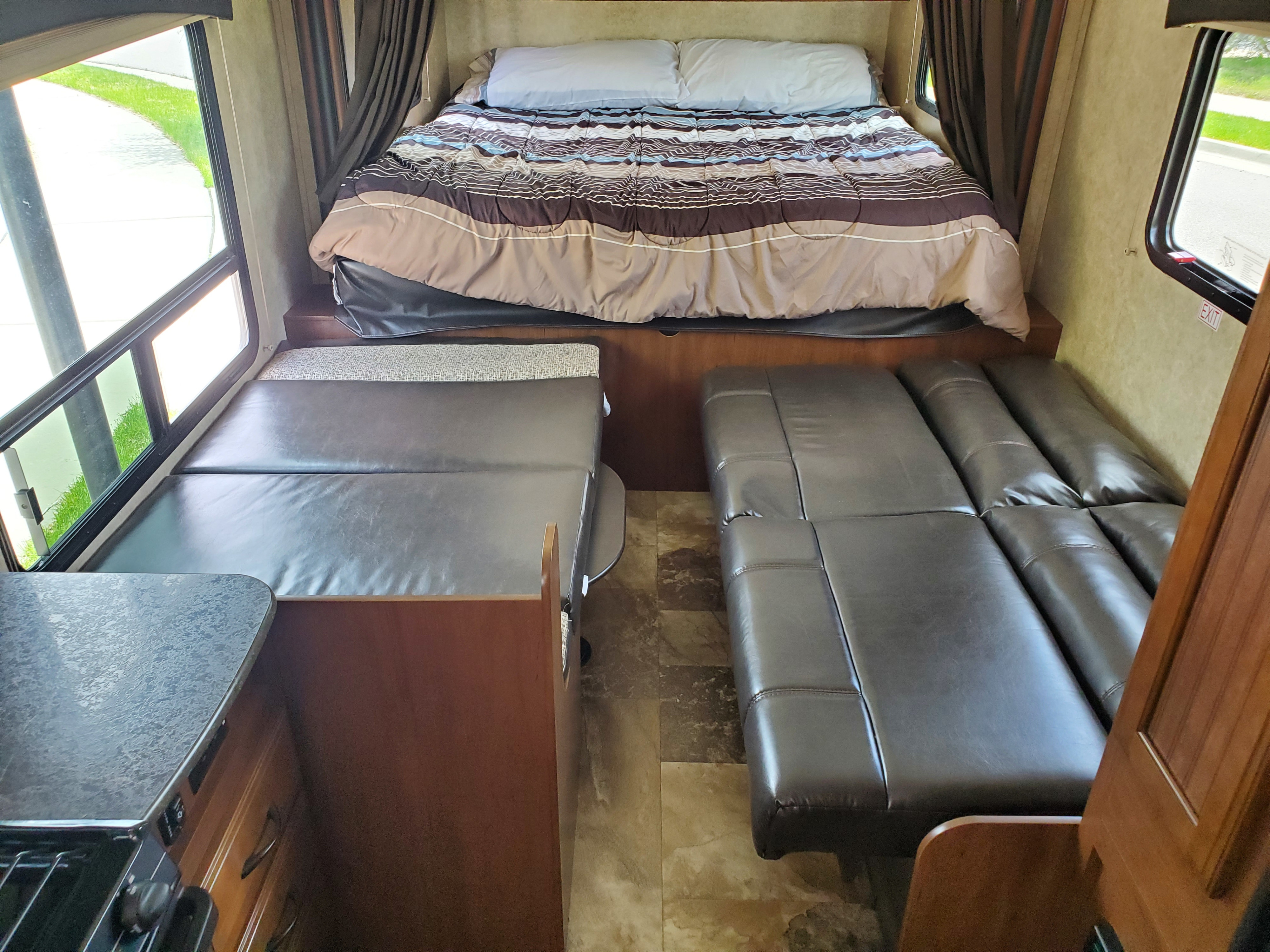 RV rental interior: comfy bed, dark leatherette sofa, dinette seating, and bright windows provide a welcoming space.. Jayco Jay Feather 2016