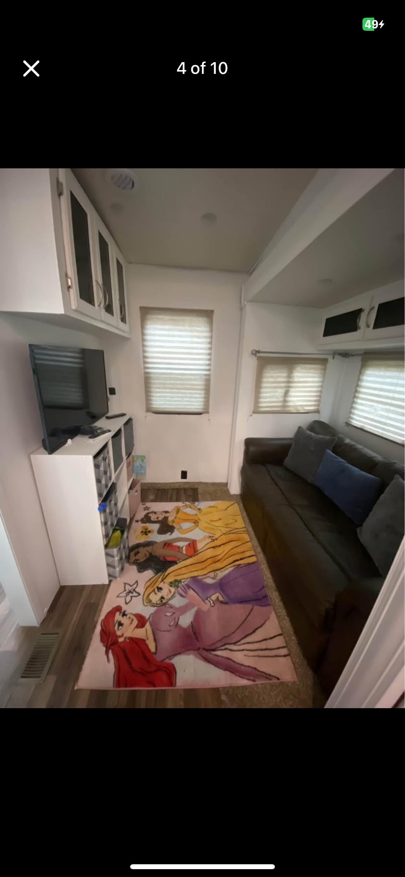 Inviting RV rental living area with TV, dark sofa, and vibrant princess rug, offering a comfortable family space.. Coachmen Chaparral 2019