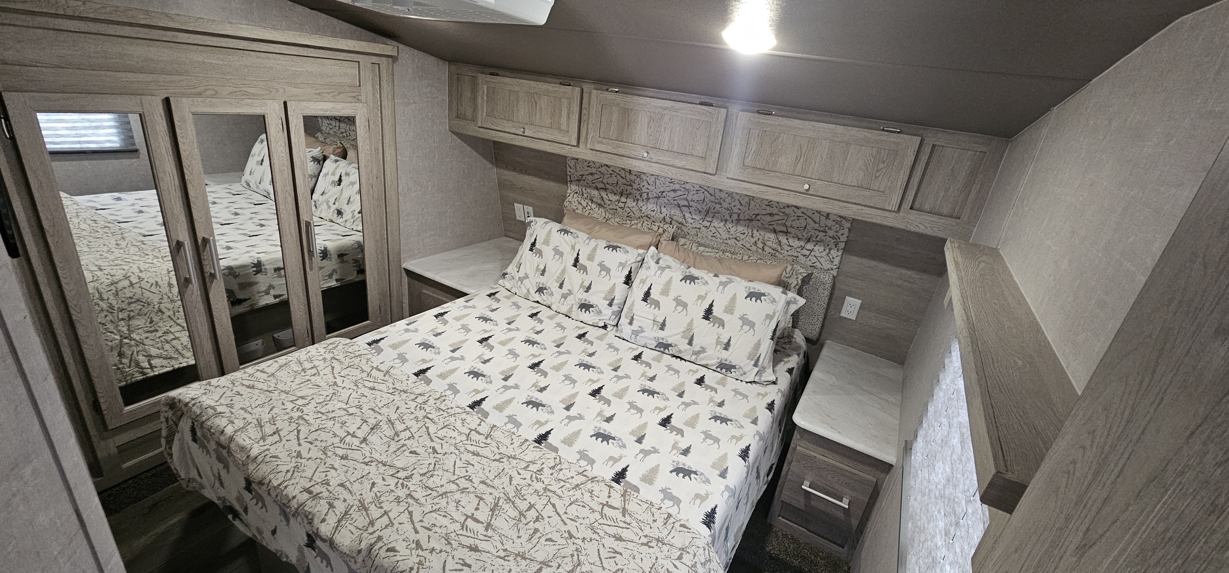 Cozy RV rental bedroom featuring nature-themed bedding, mirrored closet, and overhead storage. Ideal for adventure travel.. Eclipse Recreational Vehicles Attitude 2022