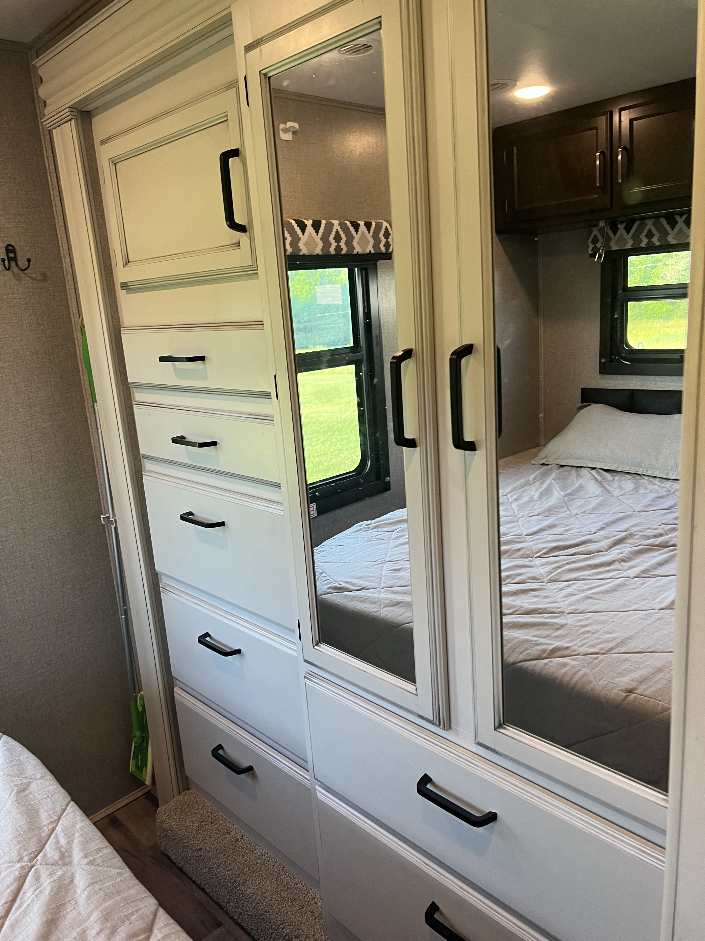 RV rental bedroom with sleek mirrored wardrobe, ample drawer storage, reflecting the cozy bed and outdoor view.. Jayco Redhawk 2021