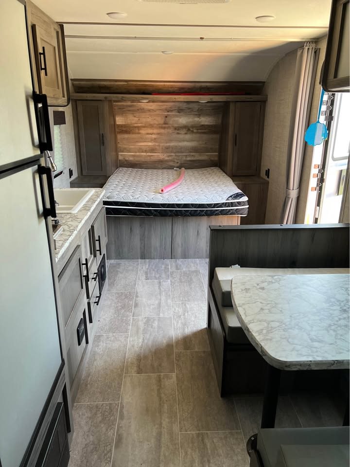 Spacious rv rental interior with a bedroom, kitchen counter and sink, and dinette table. Modern design.. Gulf Stream Grandriver bunkhouse 2021