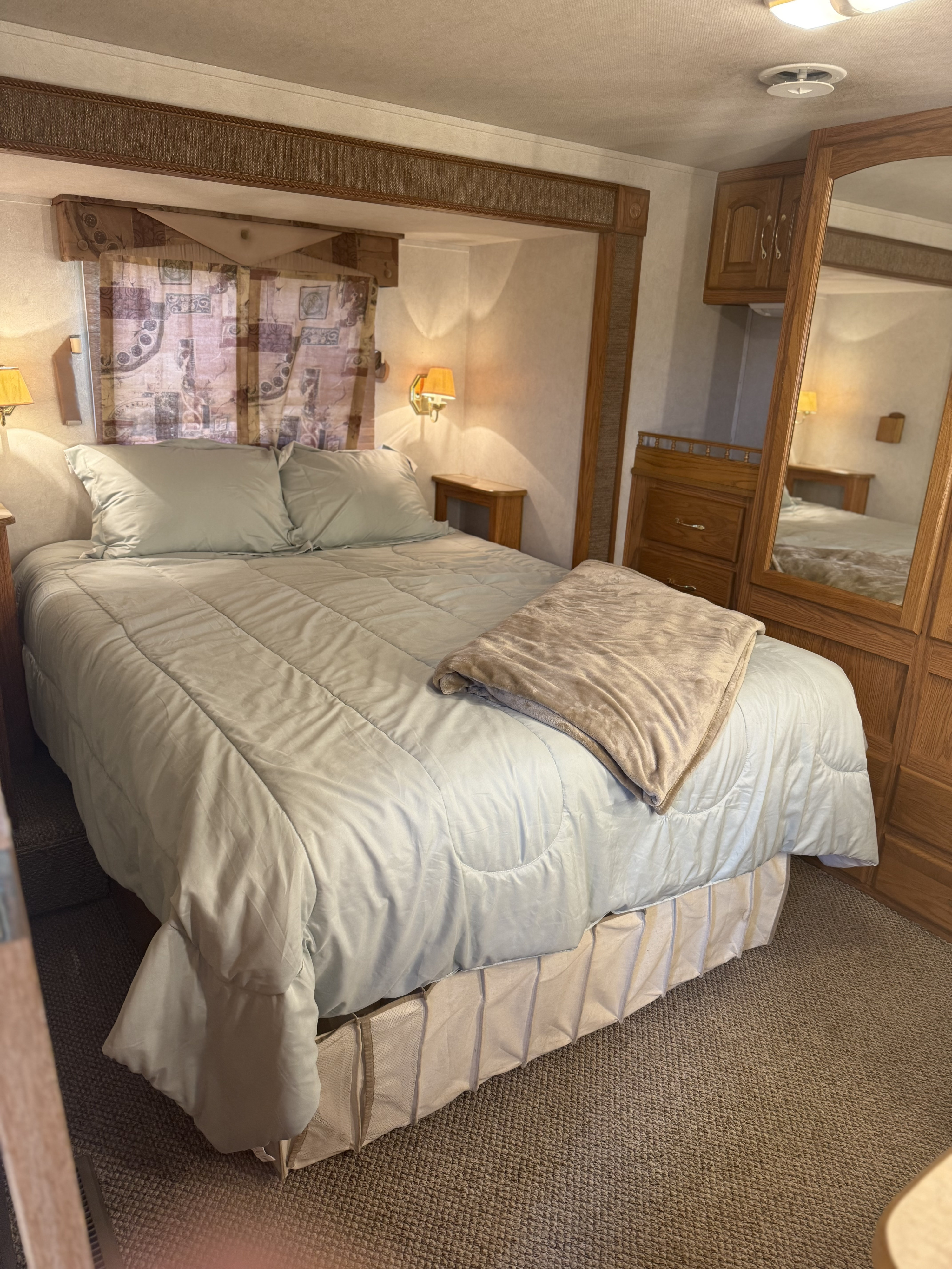 RV rental: Bedroom with light blue bedding, warm lighting, built-in storage, and a large mirror.. Damon Corporation Challenger 2003