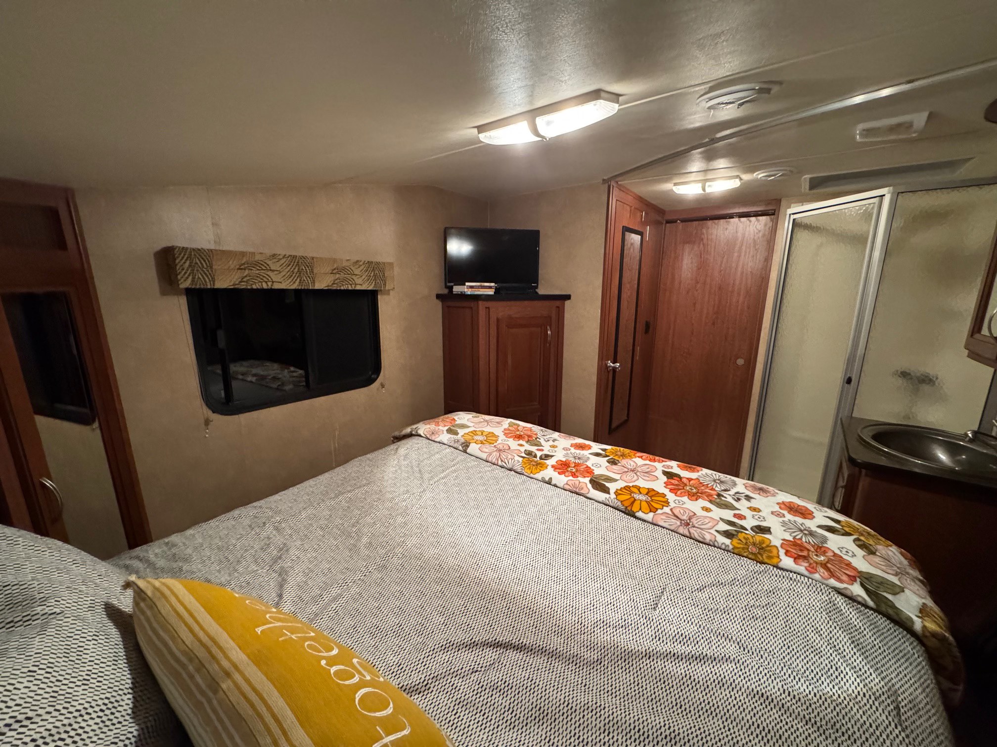 Interior view of an RV rental bedroom, showcasing a bed, TV, and en-suite bathroom with shower.. Forest River Wildcat Extralite 2012