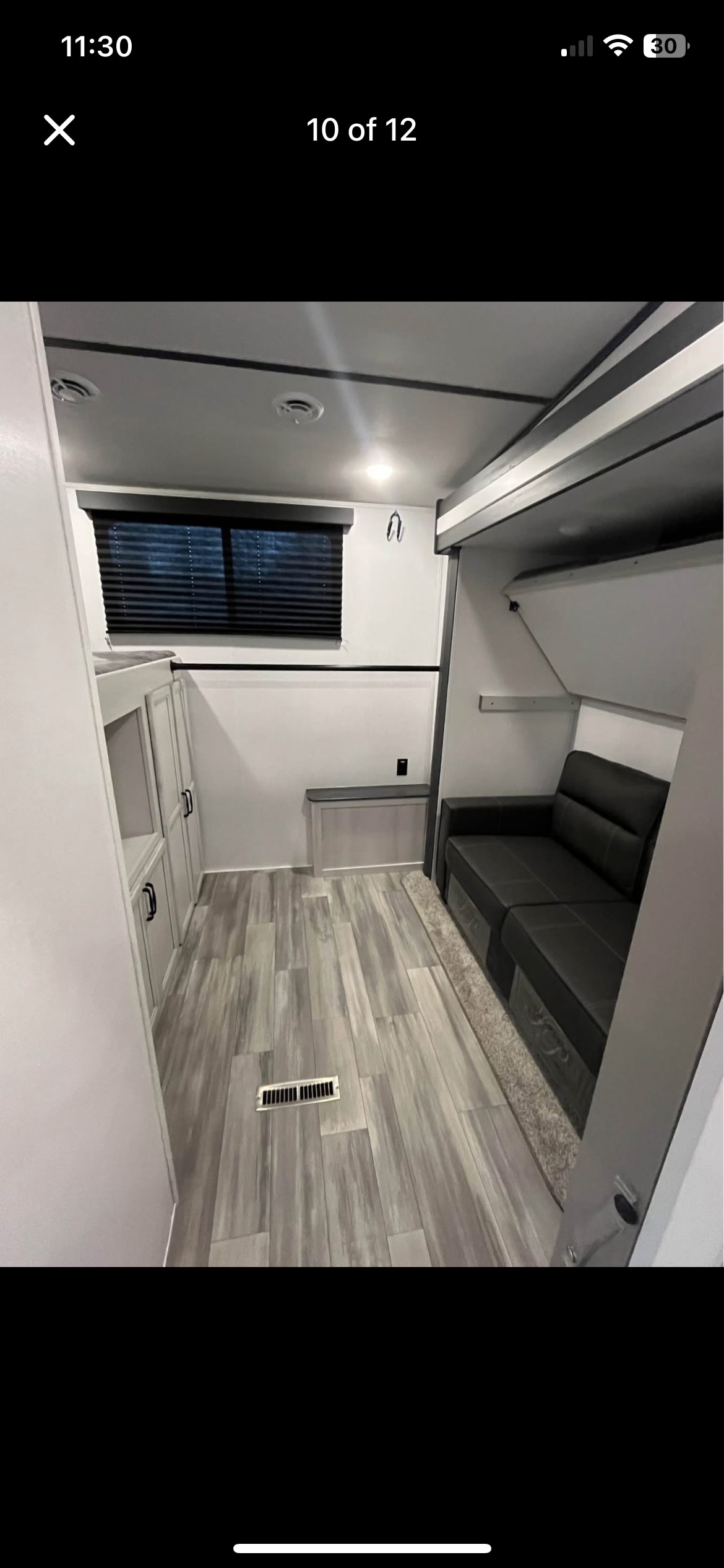 Spacious RV rental interior featuring a comfy sofa, wood-look flooring, and storage cabinets, perfect for your next adventure.. Keystone RV Sprinter 2023