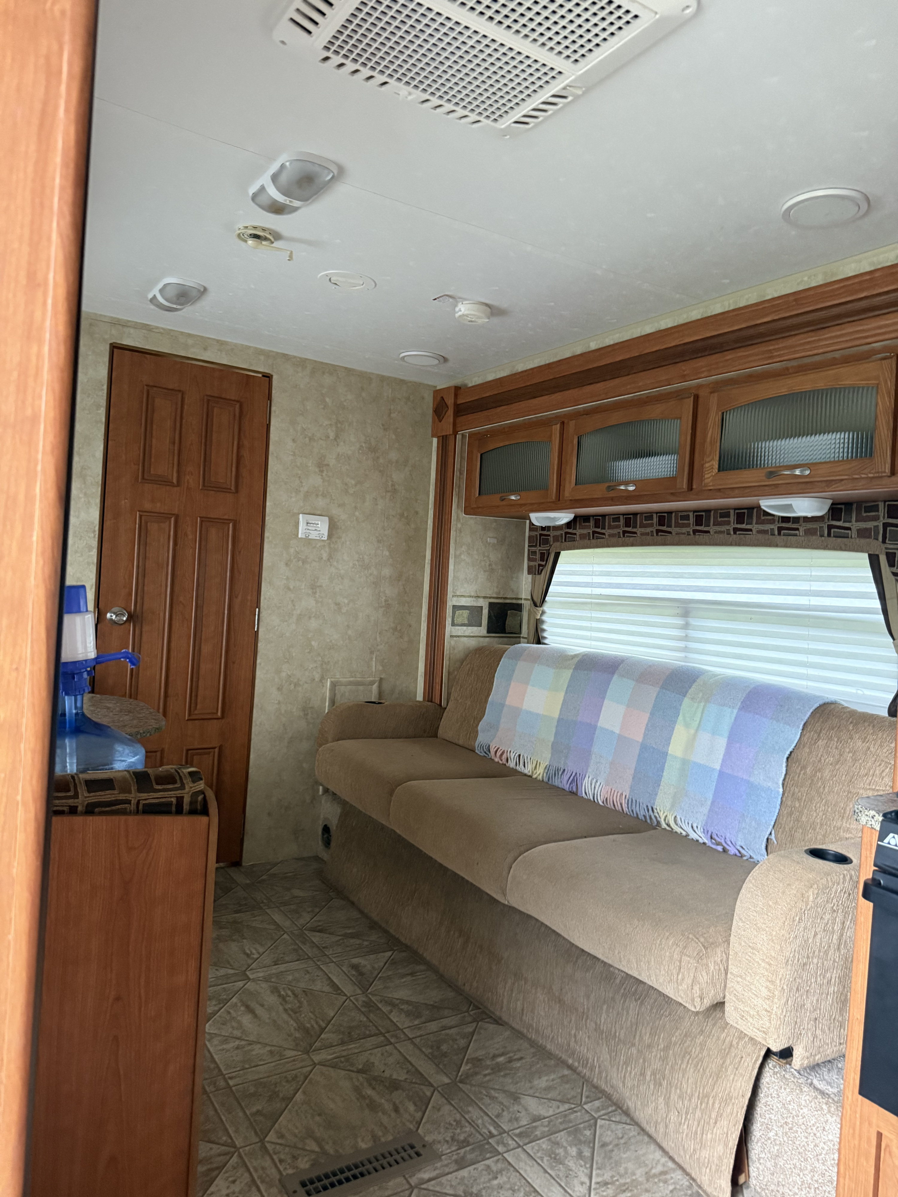 Interior of an RV rental showing a spacious living area with a beige sofa, wood cabinets, and patterned floor. Bright and inviting.. Starcraft Travel Star 2011