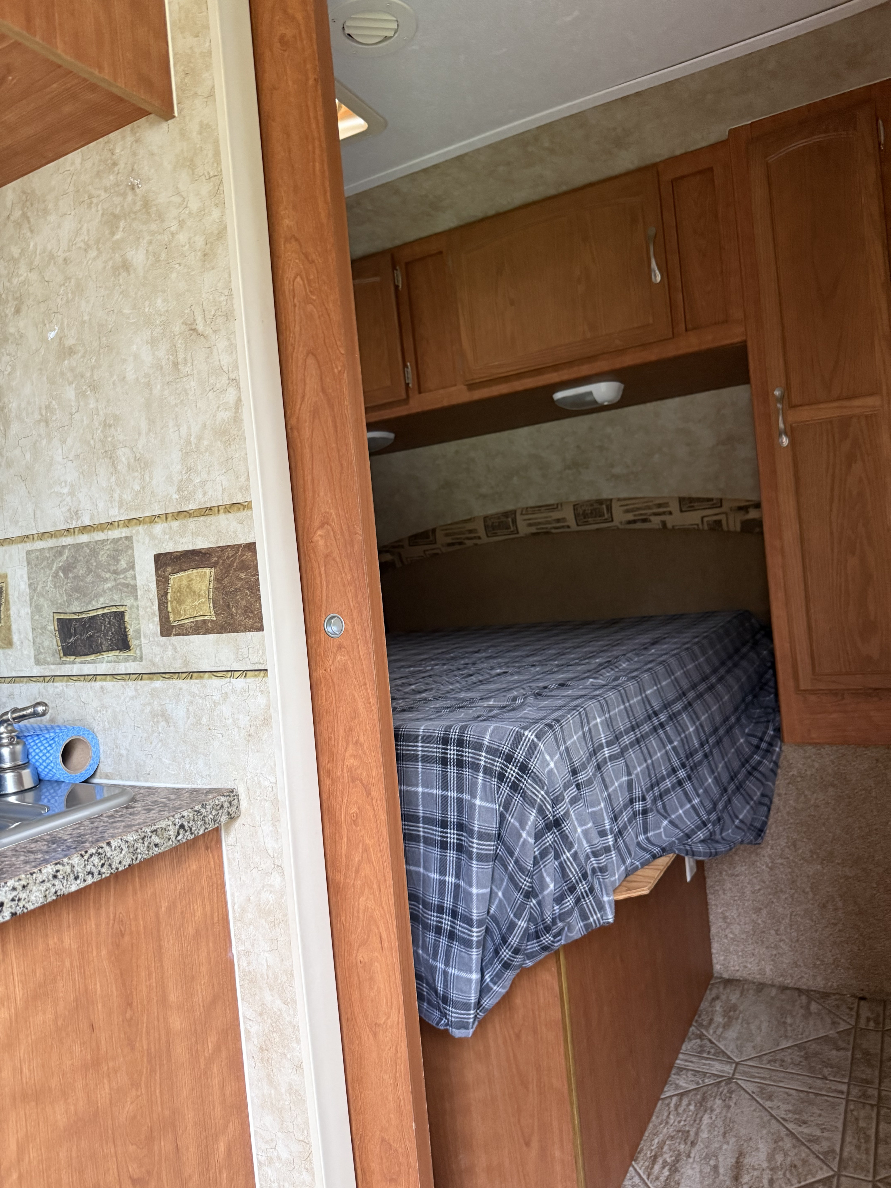 RV rental interior showcasing a cozy bedroom and compact kitchen with a sink.. Starcraft Travel Star 2011