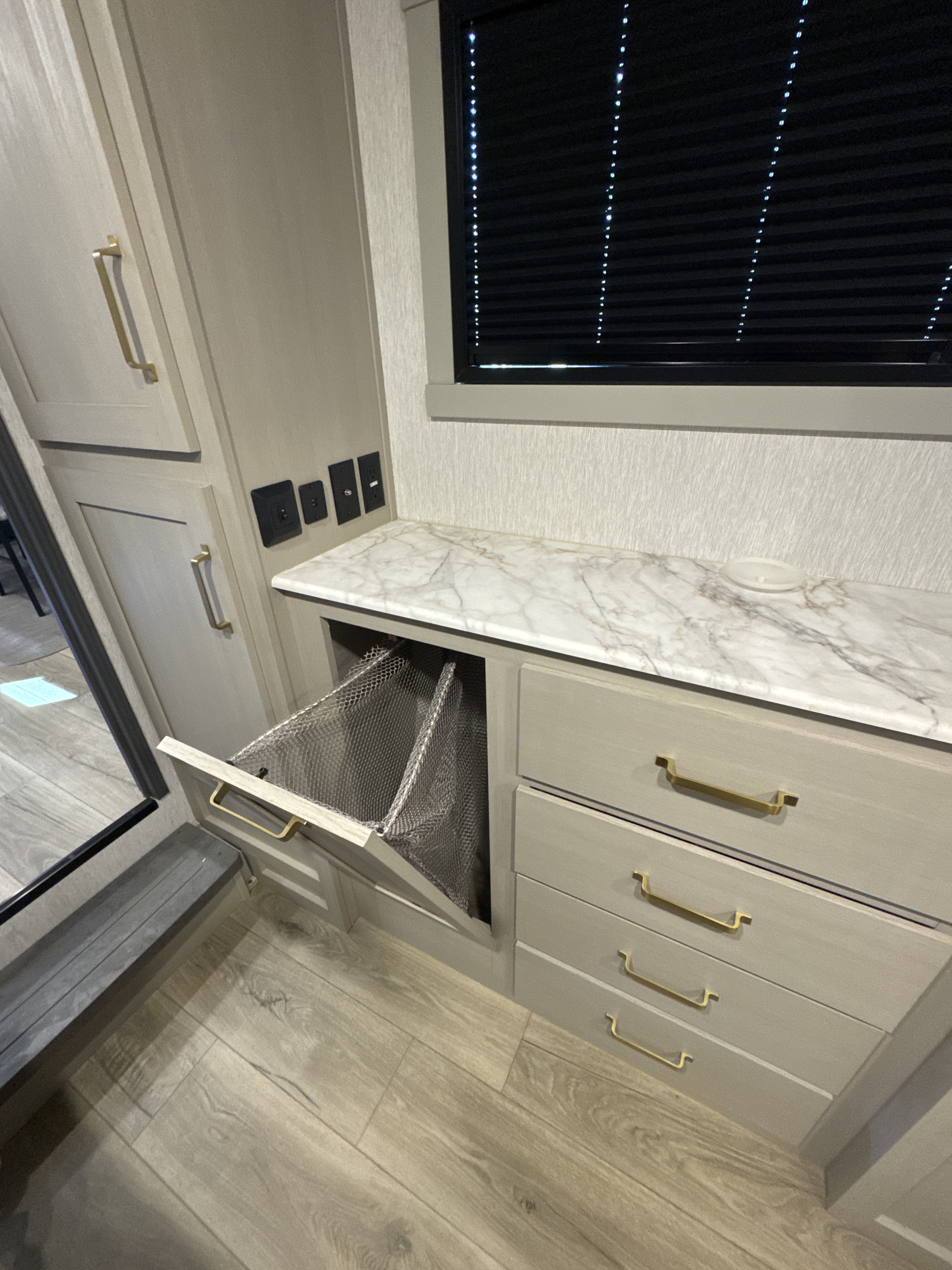 Modern rv rental interior showcasing clever storage: pull-out hamper, marble countertop, and ample cabinets.. Forest River Salem Hemisphere 2024