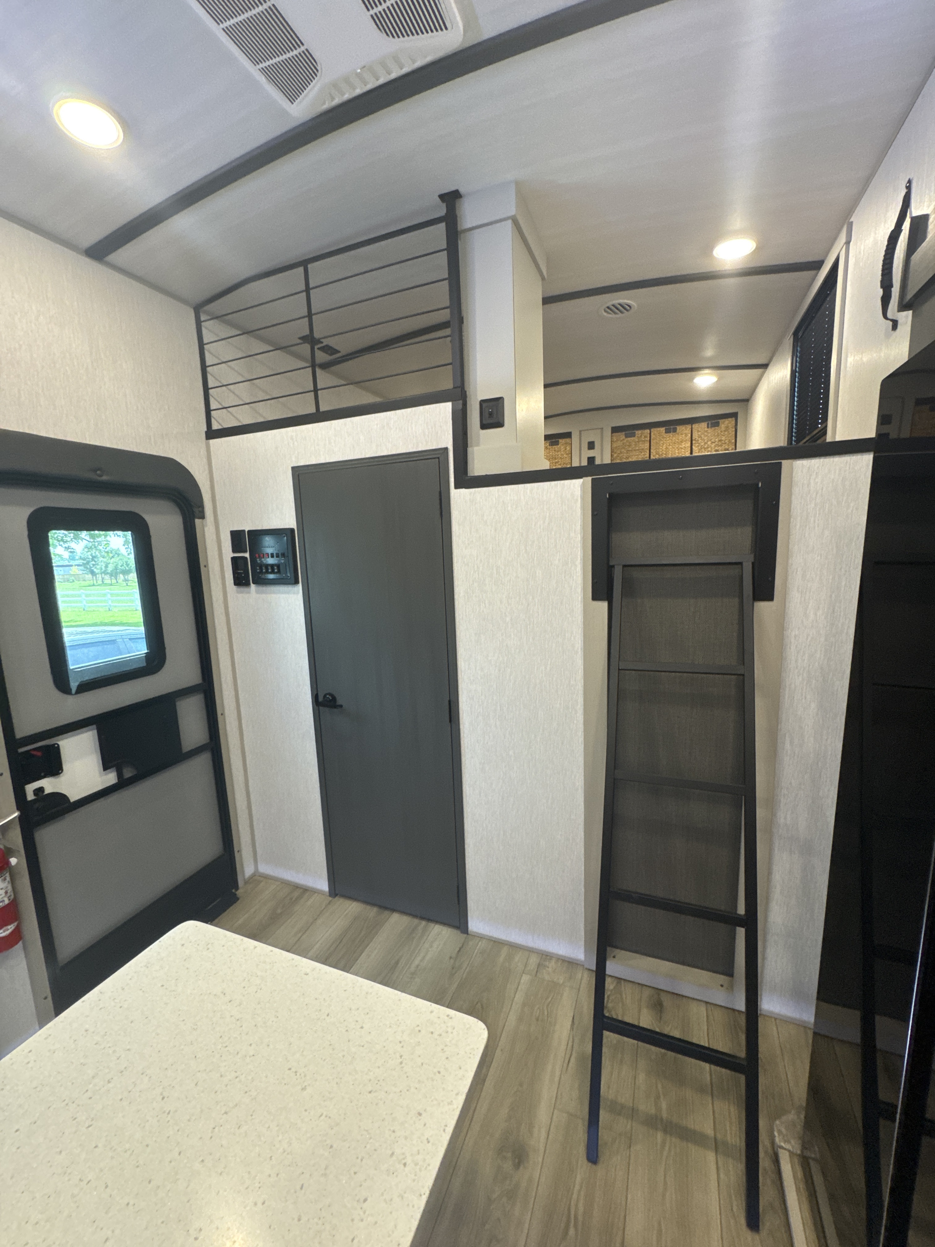 RV rental interior: light walls, wood floor, loft with ladder access, main door, and interior door with controls.. Forest River Salem Hemisphere 2024