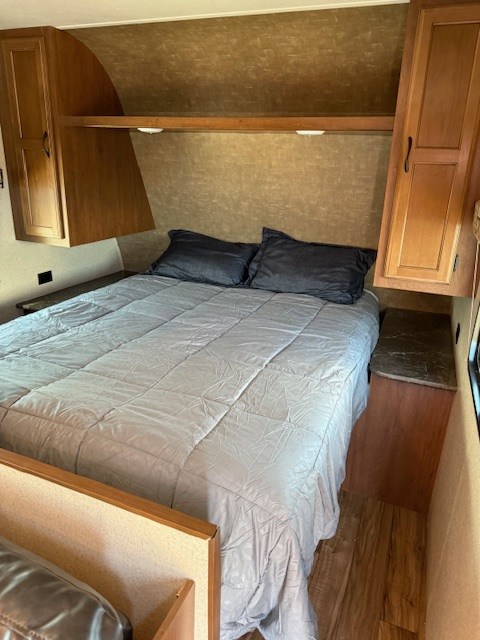 RV rental bedroom: A large bed with grey bedding, overhead cabinets, and side shelves.. Jayco Jay Flight SLX 2016