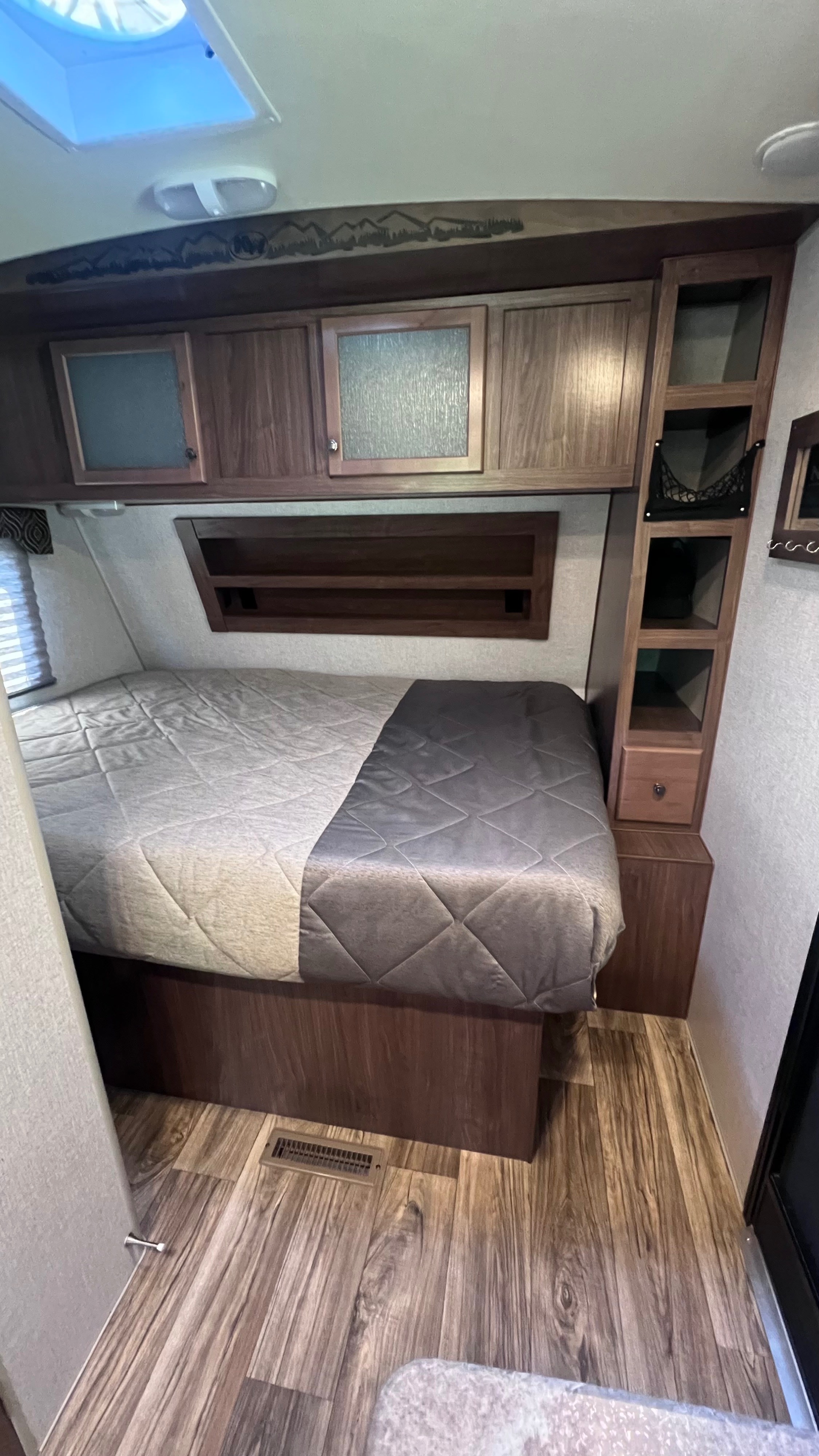 RV rental: Cozy bedroom with bed, skylight, wood-look floor, overhead cabinets, and ample built-in storage for comfort.. Nash Nash Trailer 2022