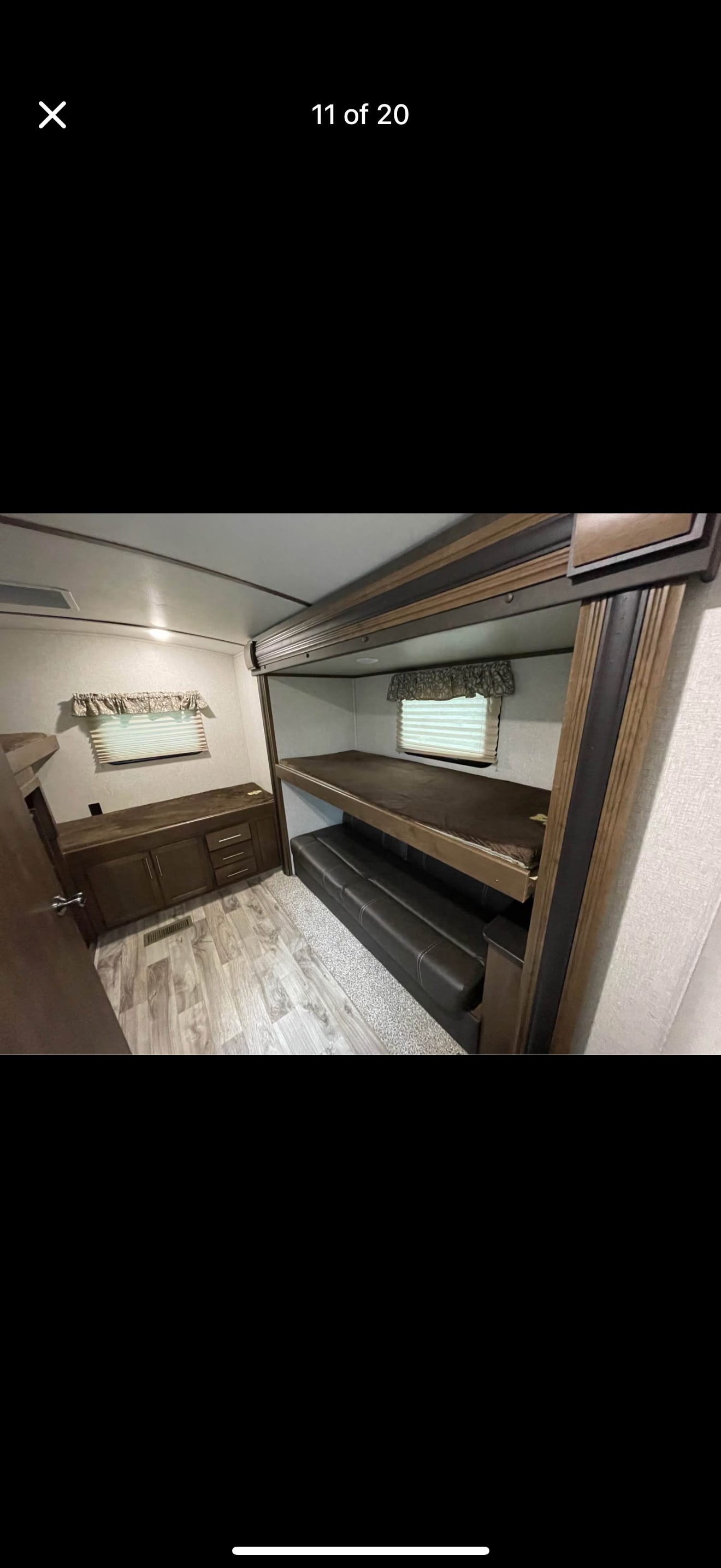 RV rental bunkhouse interior featuring an upper bunk, convertible sofa, built-in storage, and windows.. Keystone RV Cougar 2019