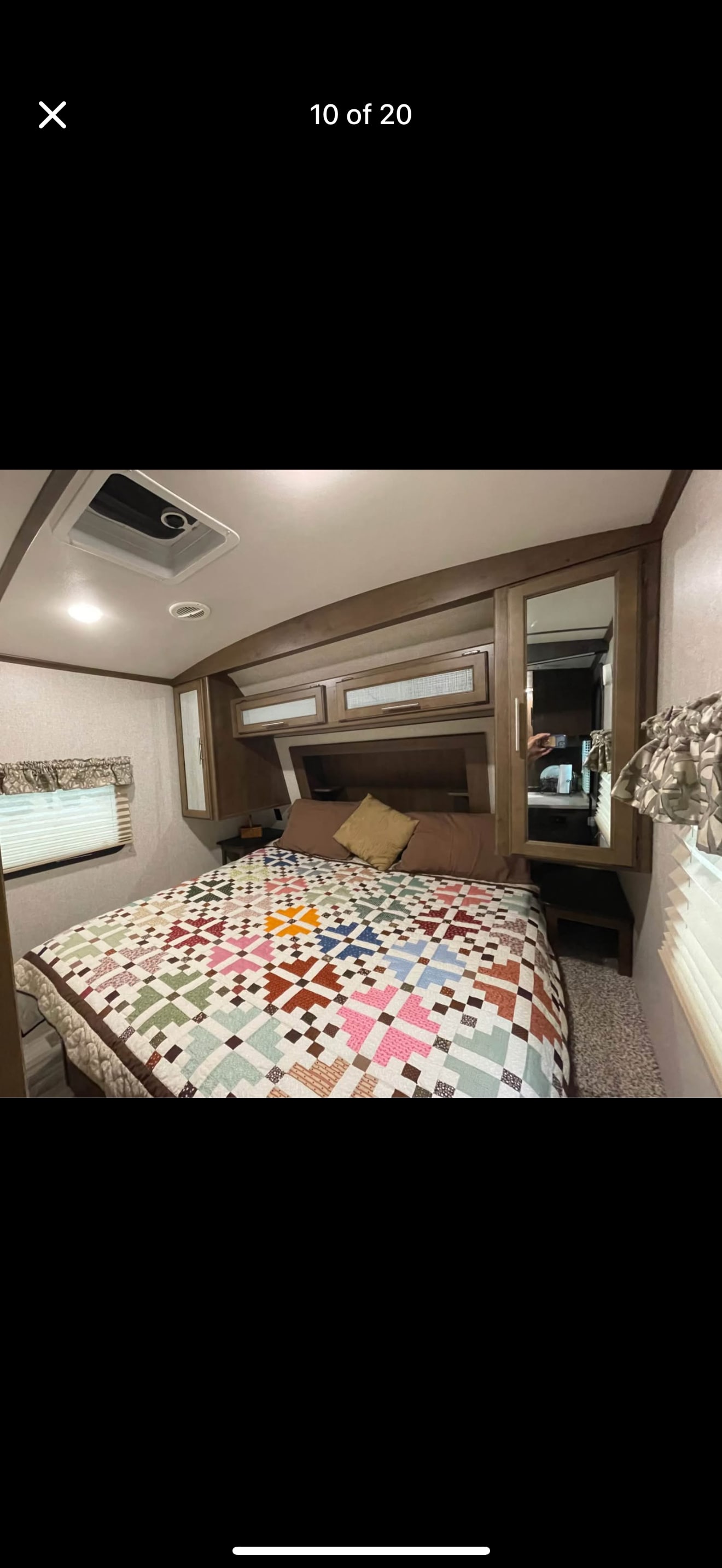 Cozy RV rental bedroom with a colorful quilt, overhead storage, and window for your travels.. Keystone RV Cougar 2019