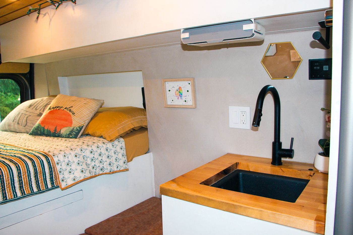 Interior of an RV rental showing a cozy bed on the left and a compact kitchen with a black sink and wooden counter on the right.. Dodge Ram 1500 2022