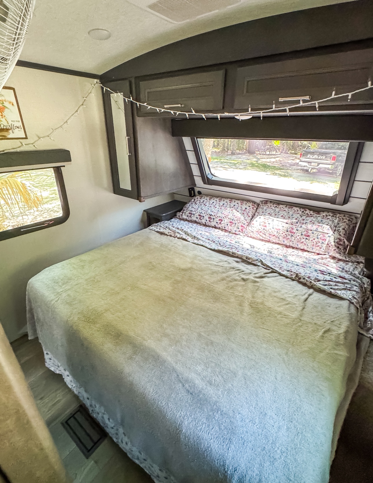 Cozy RV rental bedroom with a comfy bed, windows showing nature, and string lights. Perfect for travel.. Keystone RV Cougar 2024