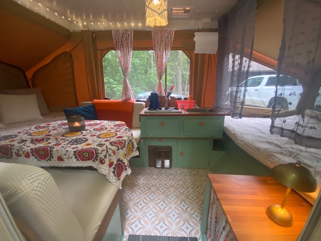 Inside a vibrant RV rental: patterned floors, beds, table with candle, and kitchen area, perfect for glamping.. Starcraft 302-20 1989