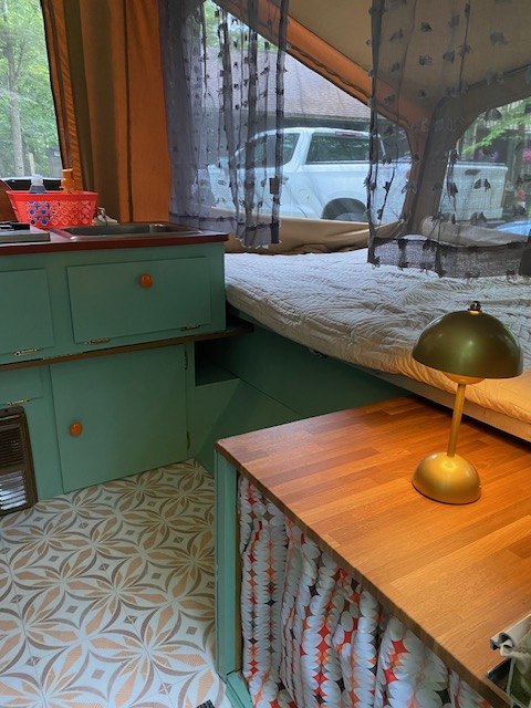 Cozy RV rental interior: turquoise kitchen, patterned floor, comfy bed, & golden lamp. Ready for adventure!. Starcraft 302-20 1989