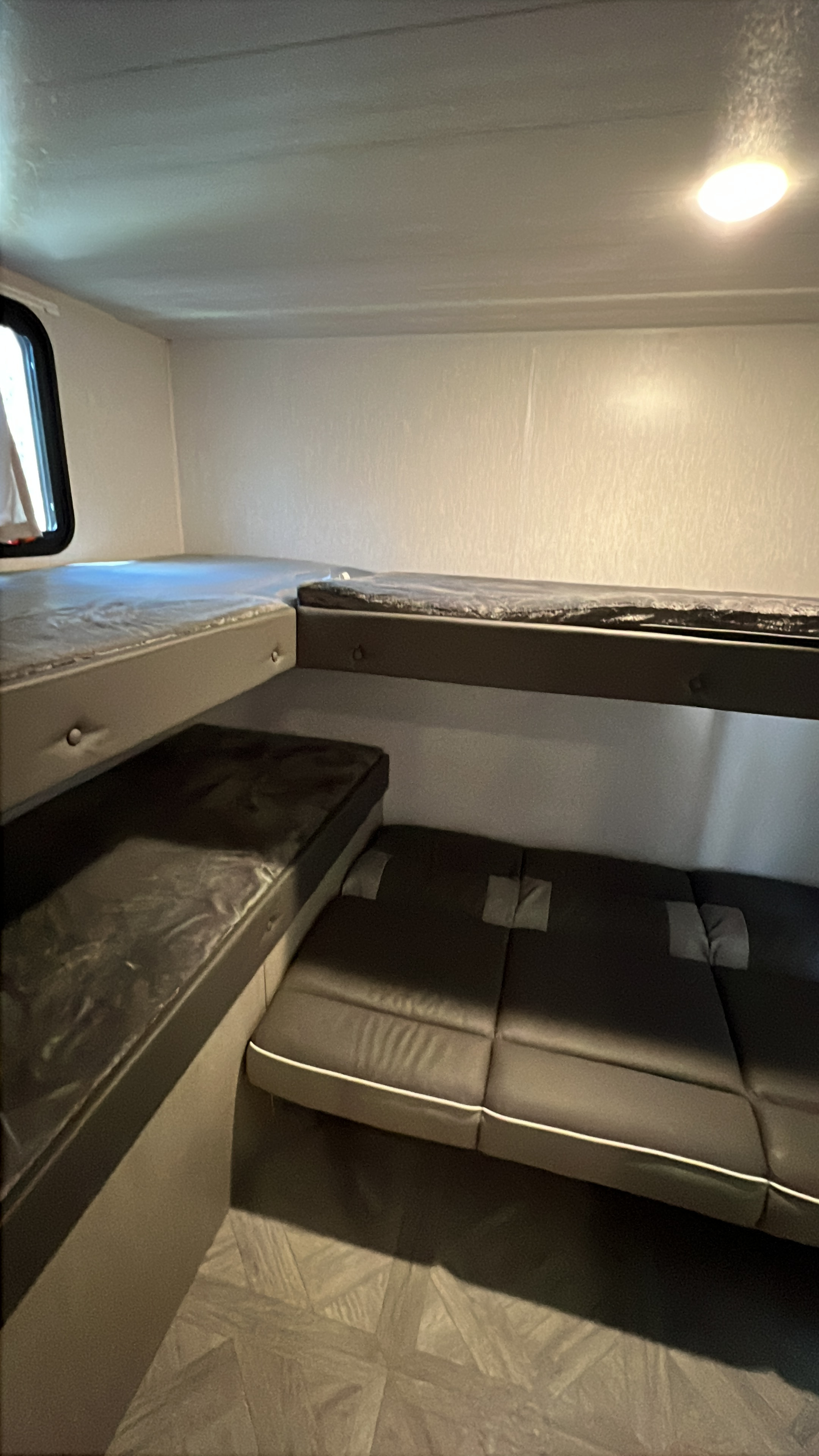 RV rental interior showcasing stacked bunk beds, one with a window view, and versatile lower seating/sleeping areas.. Forest River Salem Cruise Lite 2023