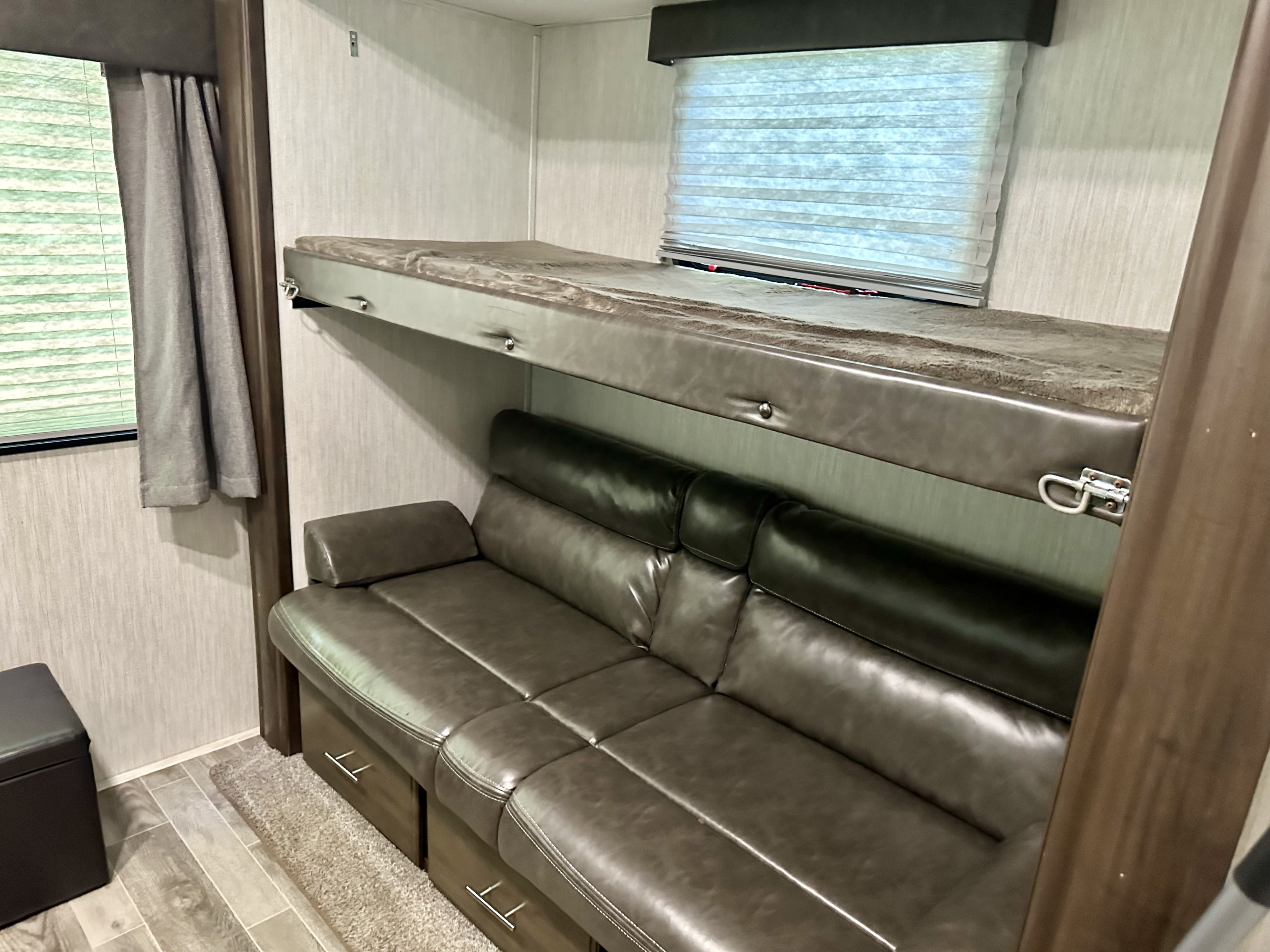 Cozy RV rental interior with a comfy gray leather couch and bunk bed, perfect for your next road trip.. Forest River Cherokee Arctic Wolf 2019