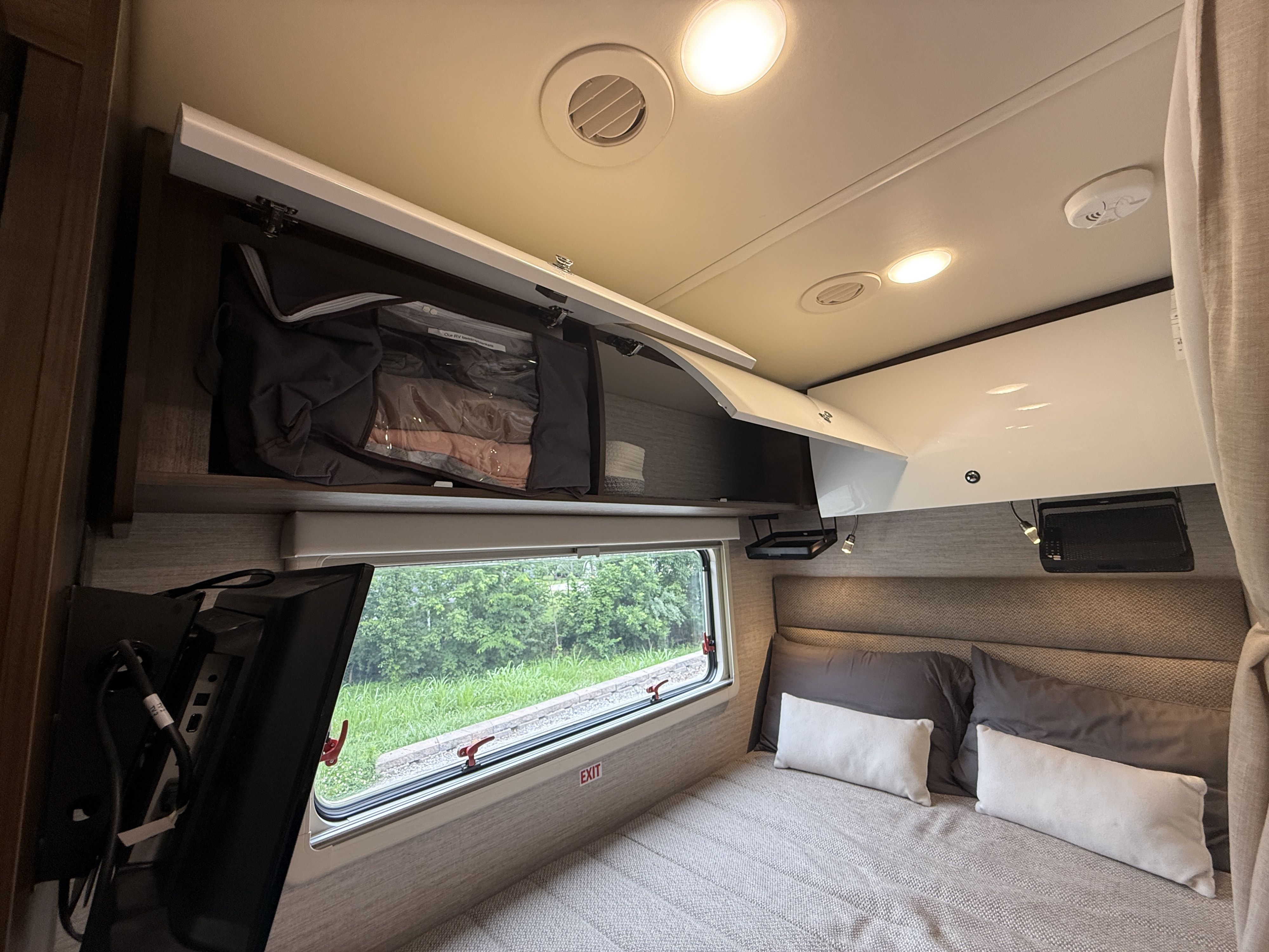 Cozy RV rental bedroom features a bed, scenic window, and accessible overhead storage, optimizing comfort for travel.. Winnebago View 2022