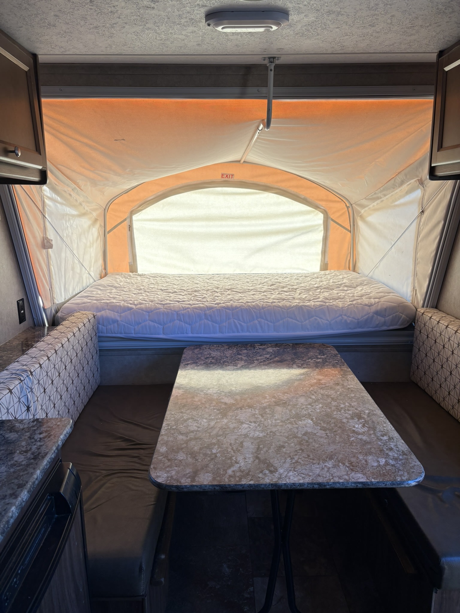 Inside a cozy pop-up camper rv rental featuring a bed, dining table, and patterned bench seating.. Forest River Viking 2016
