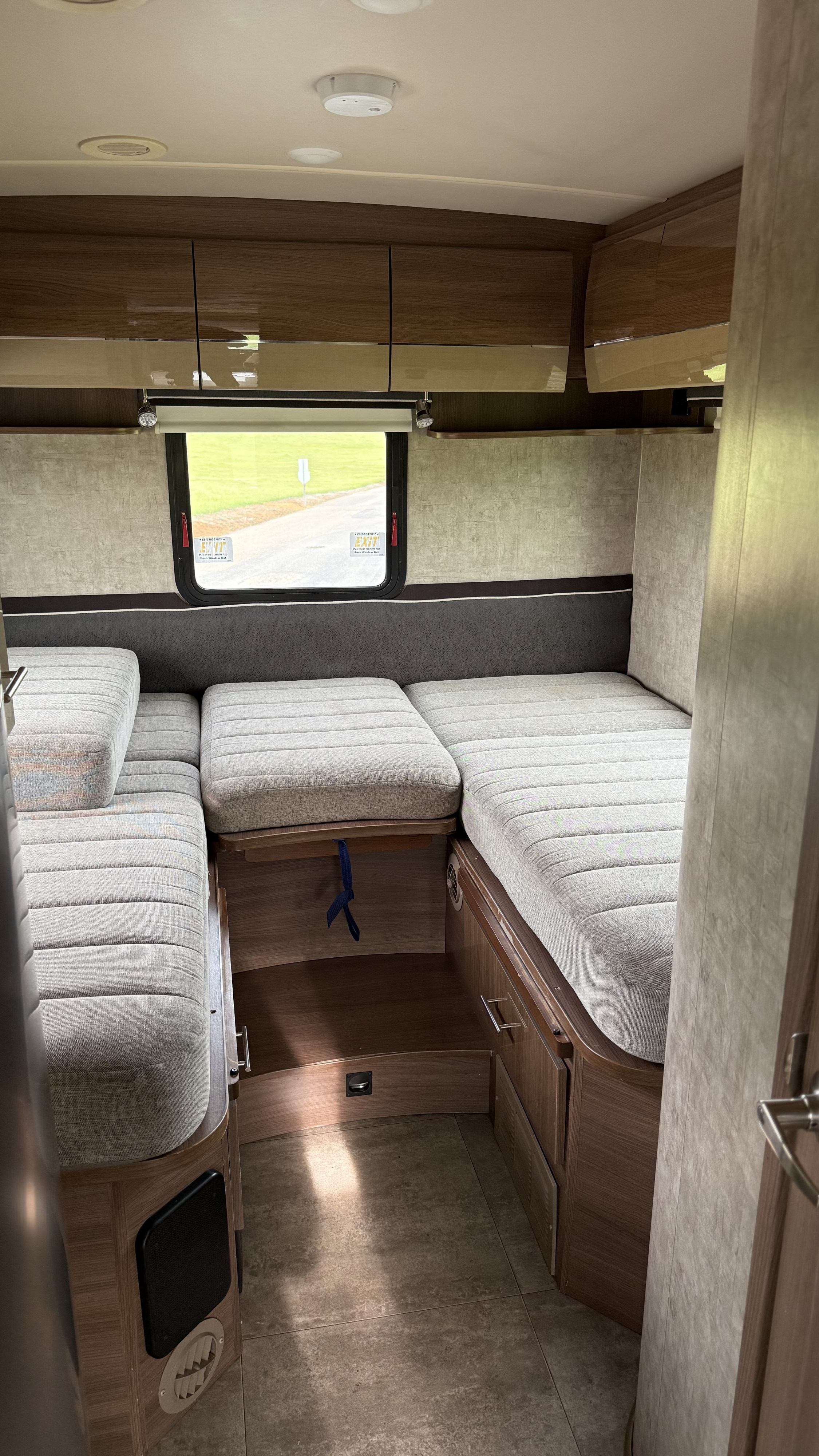 Explore this modern RV rental interior featuring versatile seating, overhead storage, and a scenic window.. Itasca Navion 2016