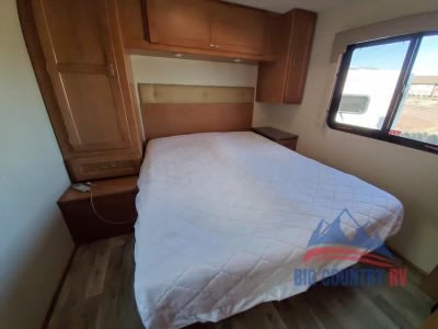 Cozy RV rental bedroom with a comfortable bed, wooden storage cabinets, and a window for natural light.. Winnebago Minnie Winnie 2017