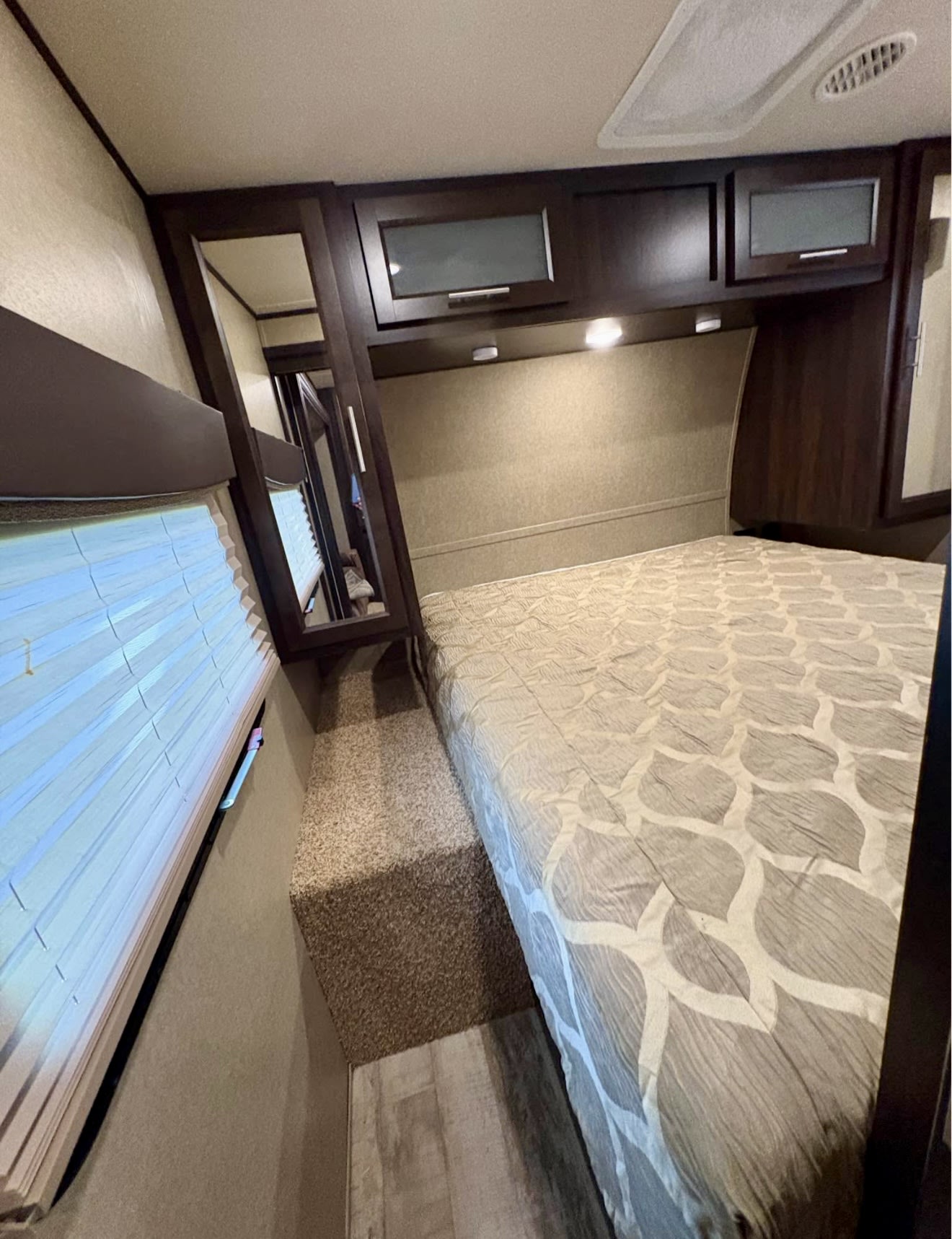 Cozy RV rental bedroom featuring a comfortable bed, overhead storage, window blinds, and a mirrored closet for your travels.. Forest River X-Lite 2016