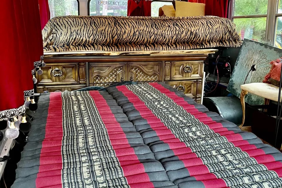 Unique RV rental interior: floor mattress with red/black pattern, ornate dresser, and tiger-print bedding.. Ford F450 2008
