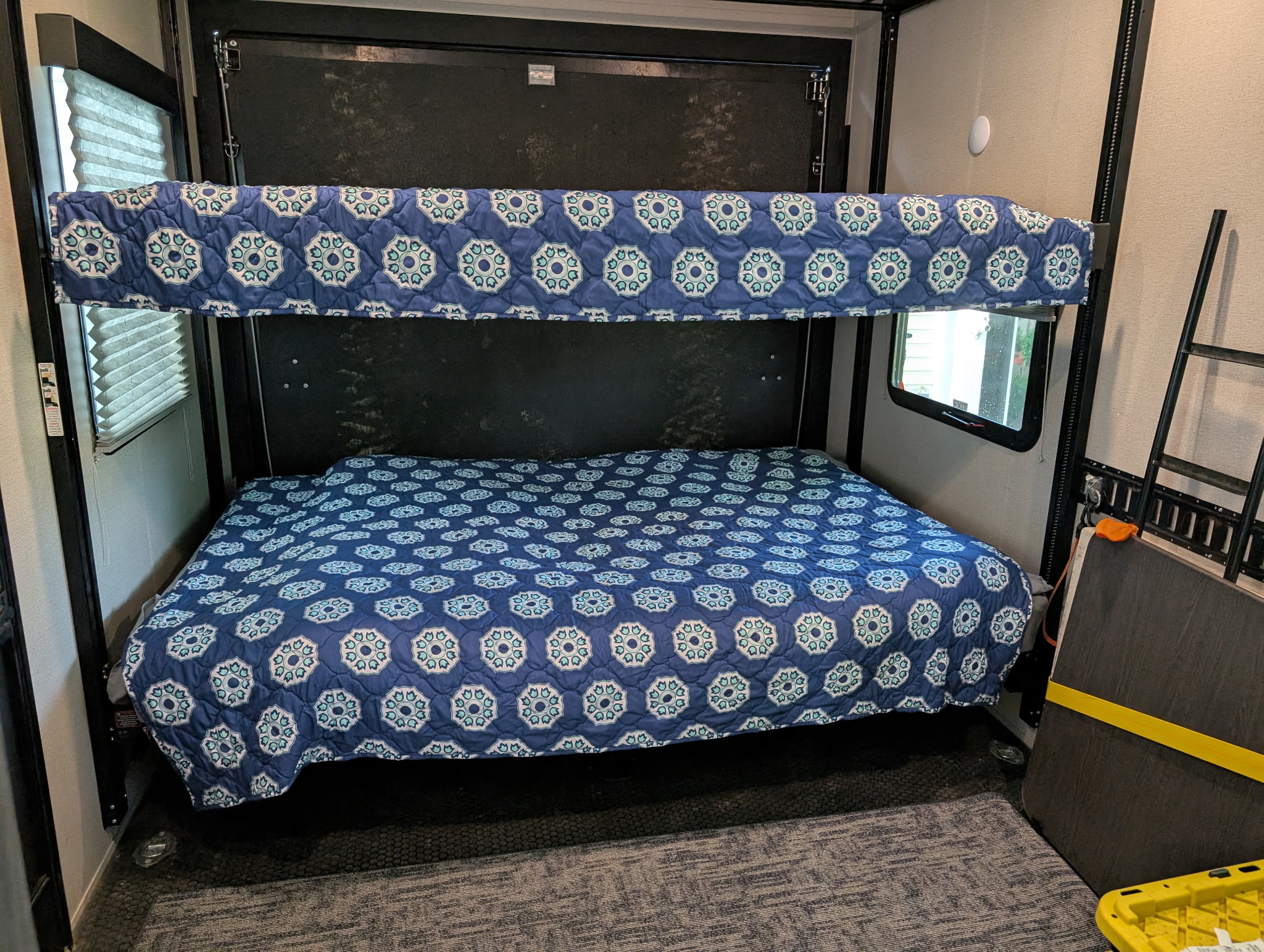 RV rental bunk beds with blue patterned comforters, offering comfy sleeping in this travel trailer setup.. Grand Design Momentum Toy Hauler 2022
