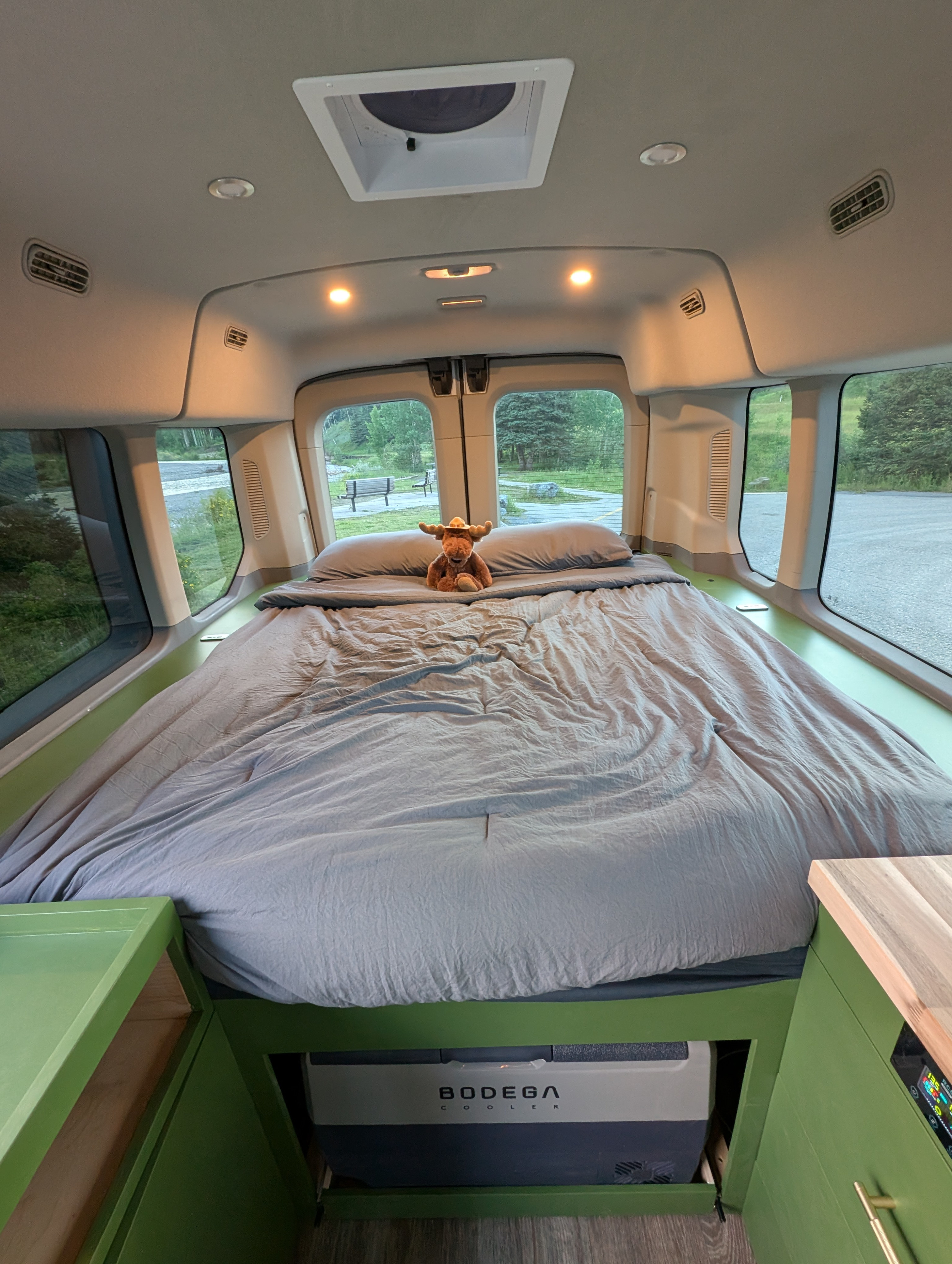 Cozy RV rental interior featuring a comfy bed, under-bed cooler, and scenic back window view.. Ford Transit 2017