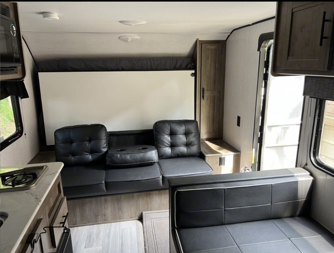 Compact rv rental interior with a versatile sofa, kitchen counter, and space-saving wall bed. Perfect for travel adventures.. Heartland RVs Pioneer Trail Blazer 2022