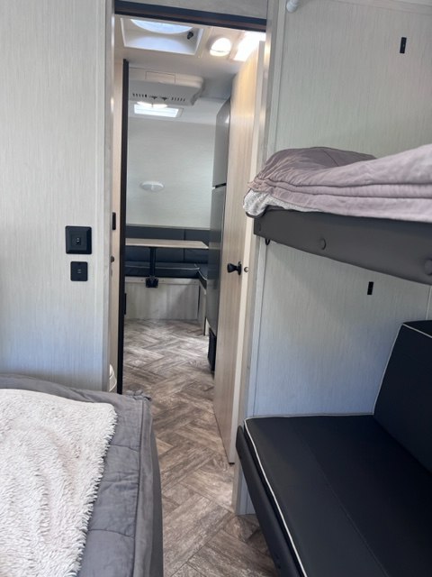 Modern RV rental interior showing a bunk bed, hallway, and dinette area, perfect for family adventures.. Forest River Wildcat 176BHX 2023