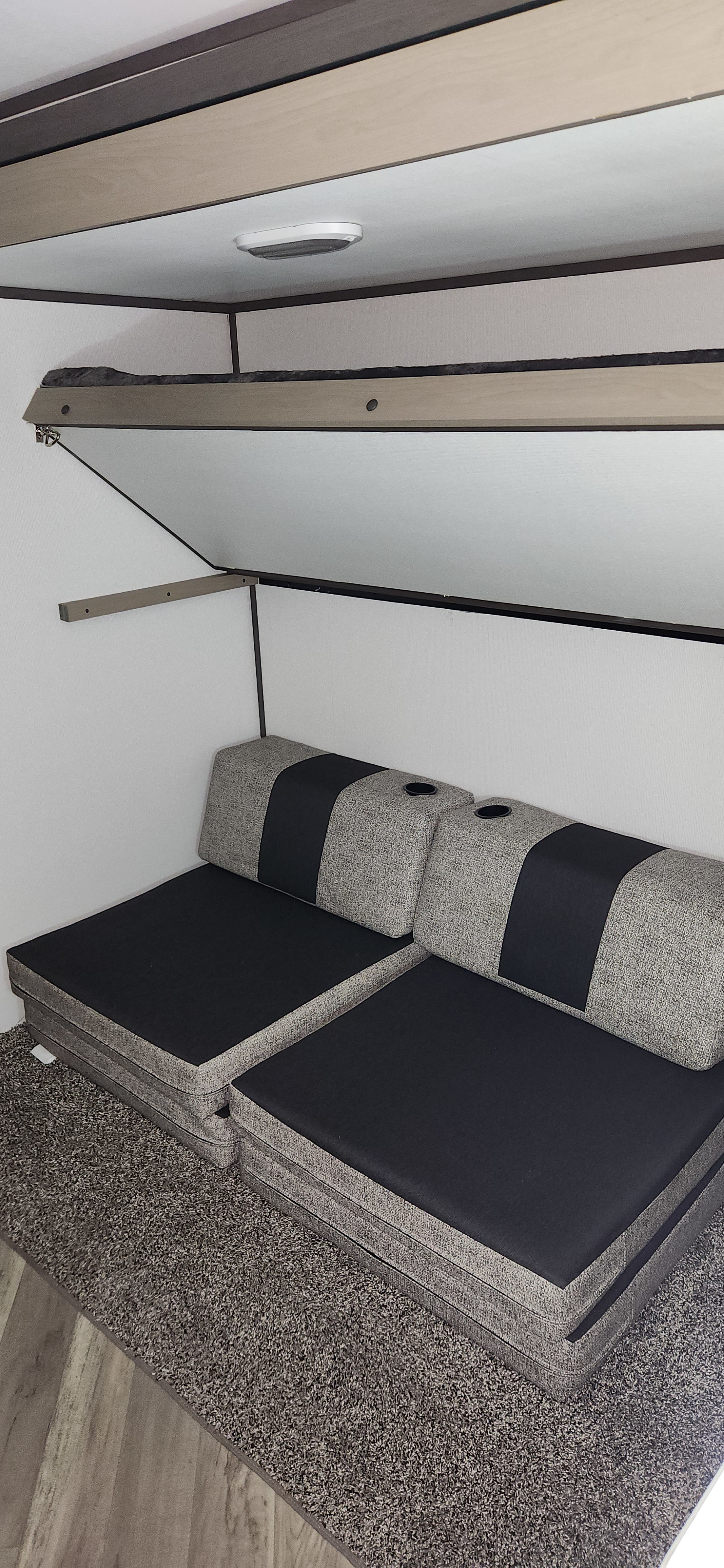 RV rental interior showcasing a convertible sofa with cupholders and a foldable upper bunk bed, optimizing space.. Cruiser RV Shadow Cruiser 2021