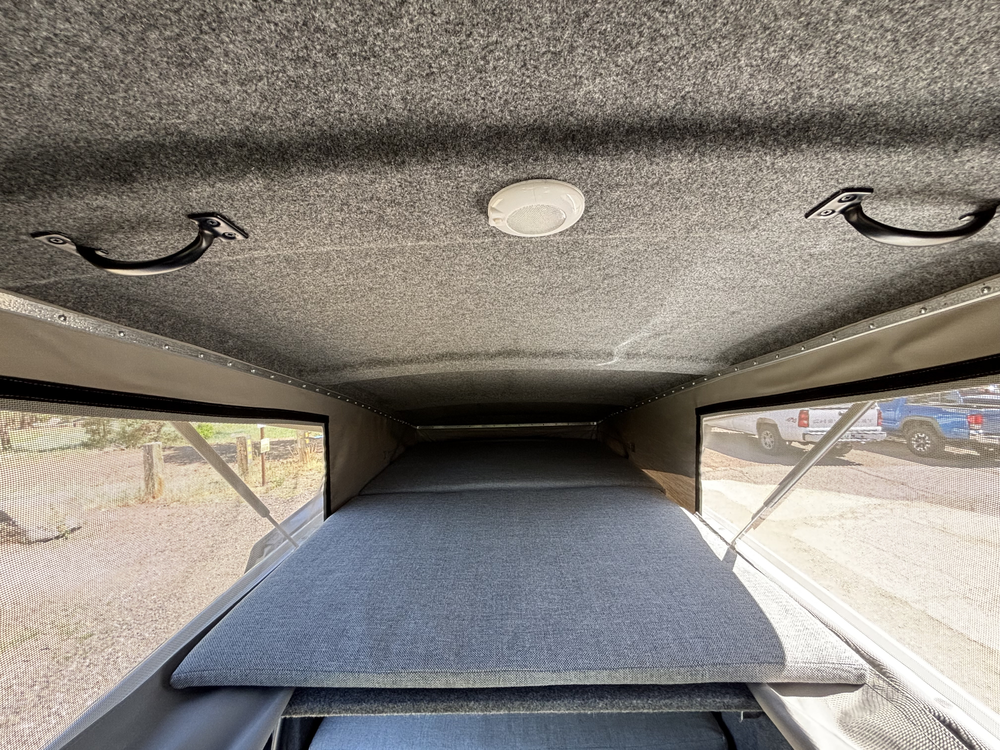 RV rental interior view: pop-top camper with a large grey bed, ceiling light, and grab handles.. Mercedes Vito Camper 2018