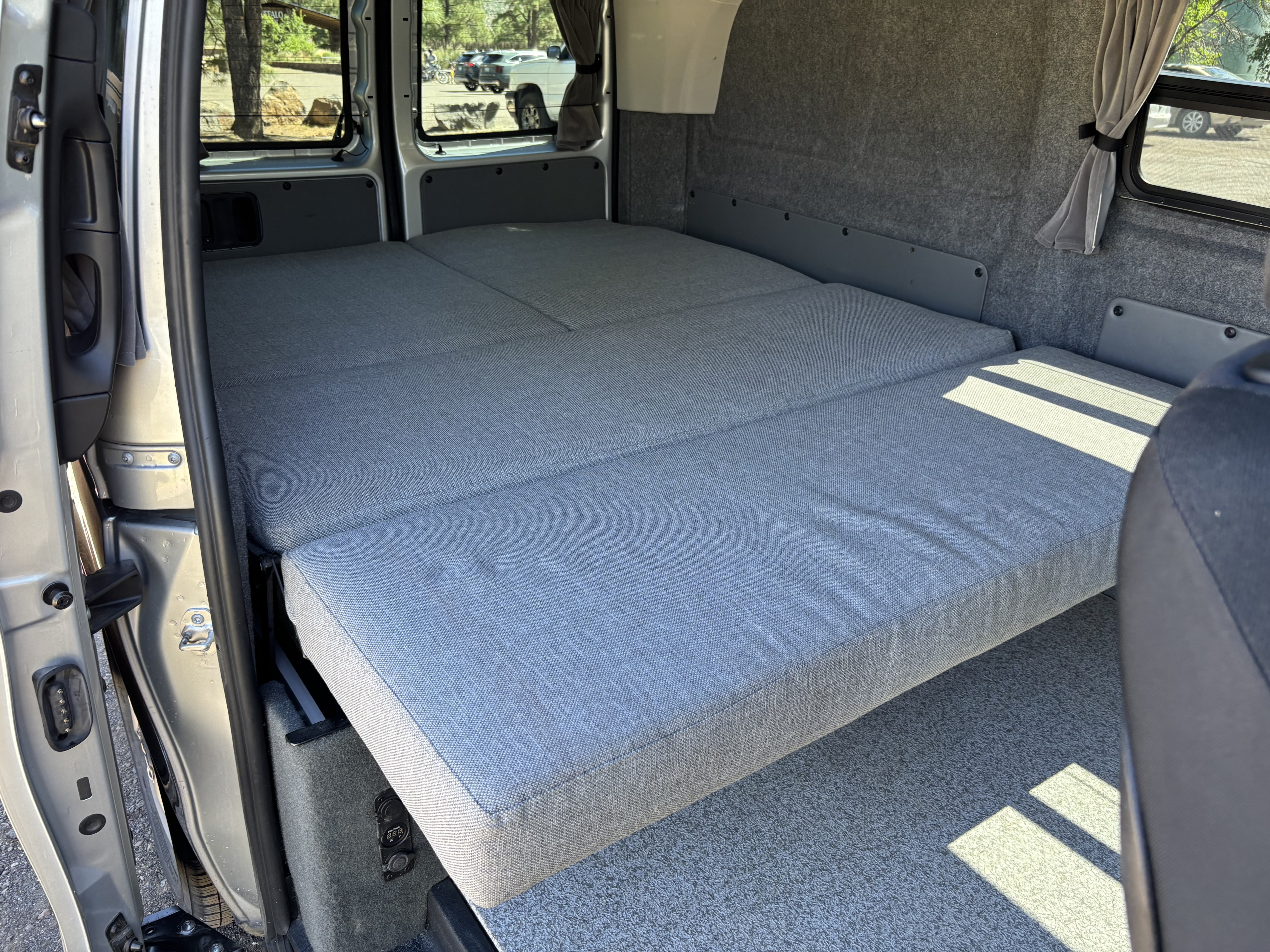 RV rental: Interior of a camper van with a gray modular bed and carpeted walls. Power outlets visible for comfy travel.. Mercedes Vito Camper 2018