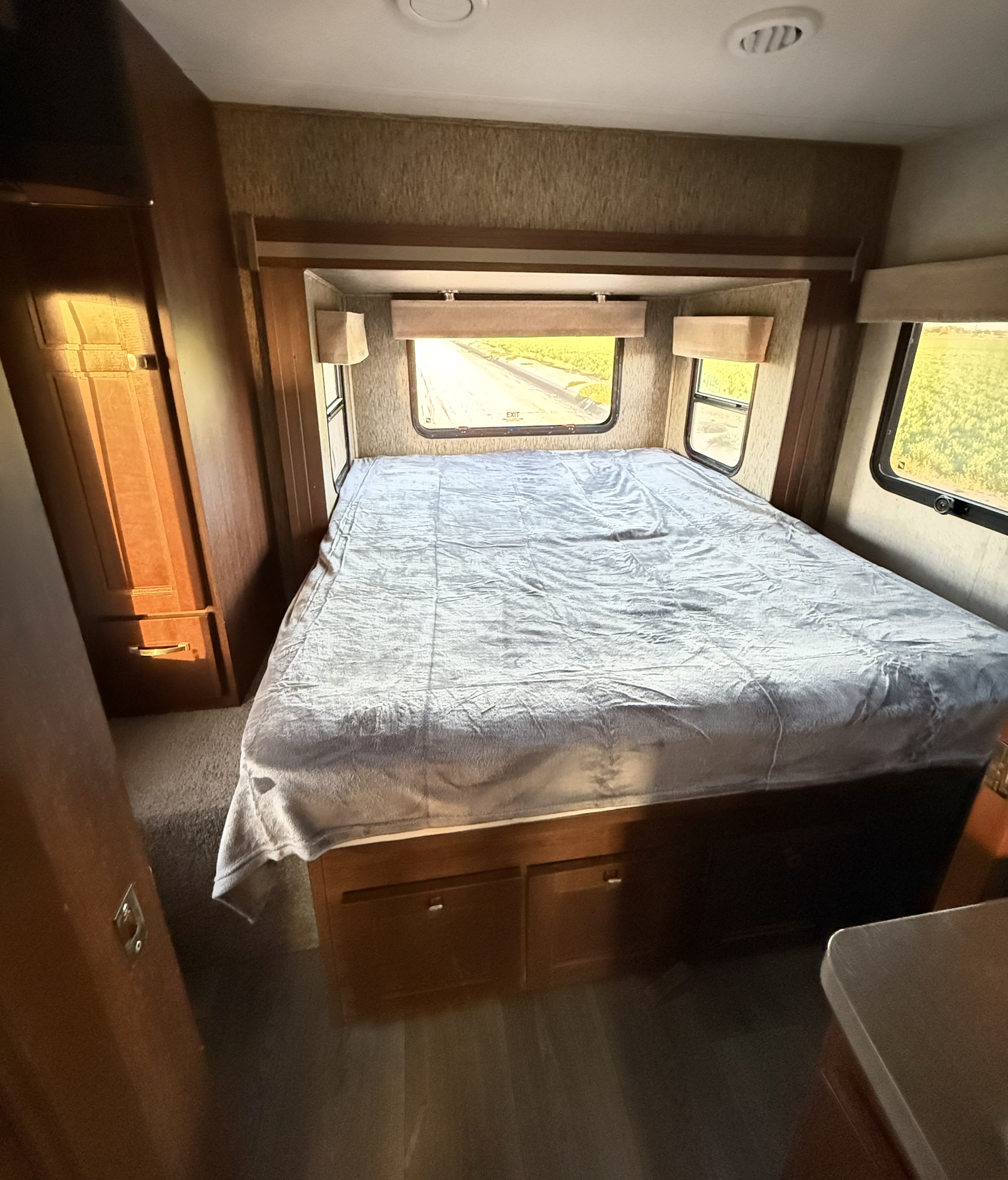Inside an RV rental: a bright bedroom features a large bed, built-in storage, and scenic window views.. Forester MBS 2018