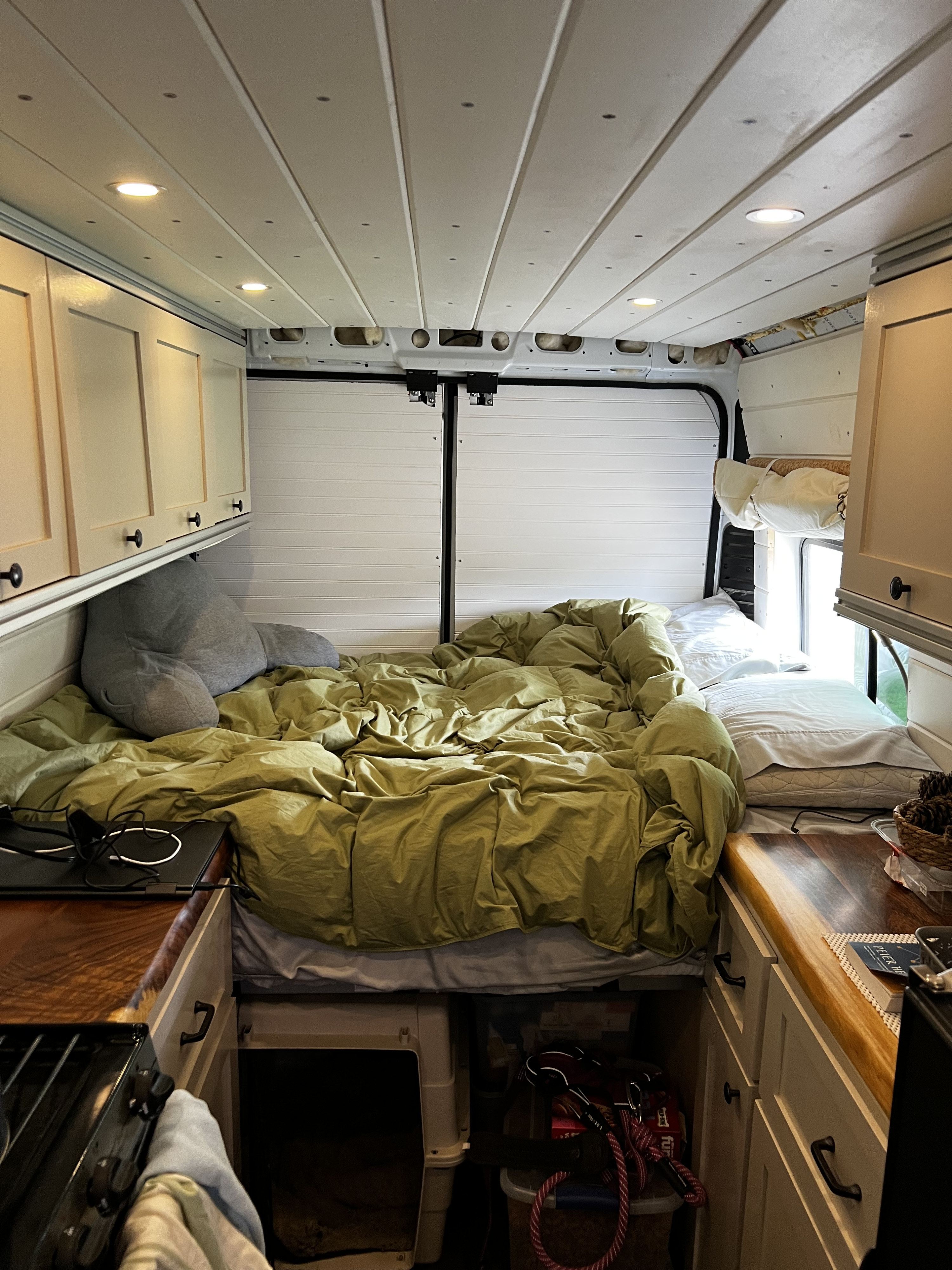This RV rental interior features a cozy bed, compact kitchen with wood counter, and pet supplies. Ready for adventure!. Ram Promaster 3500 EX 2022