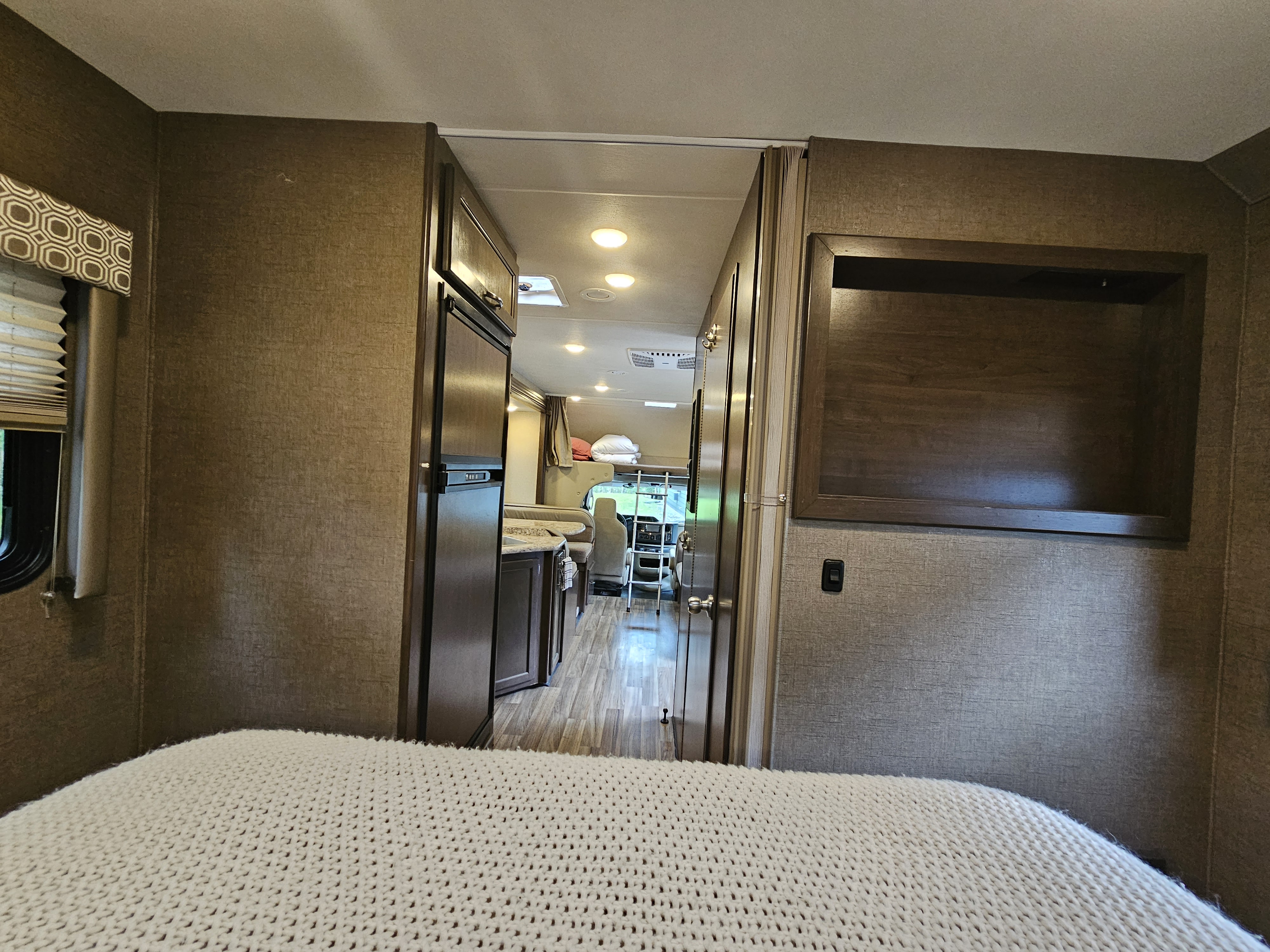 Cozy RV rental interior, from bedroom showcasing compact kitchen, living space, and front cab area.. Thor Four Winds 2019