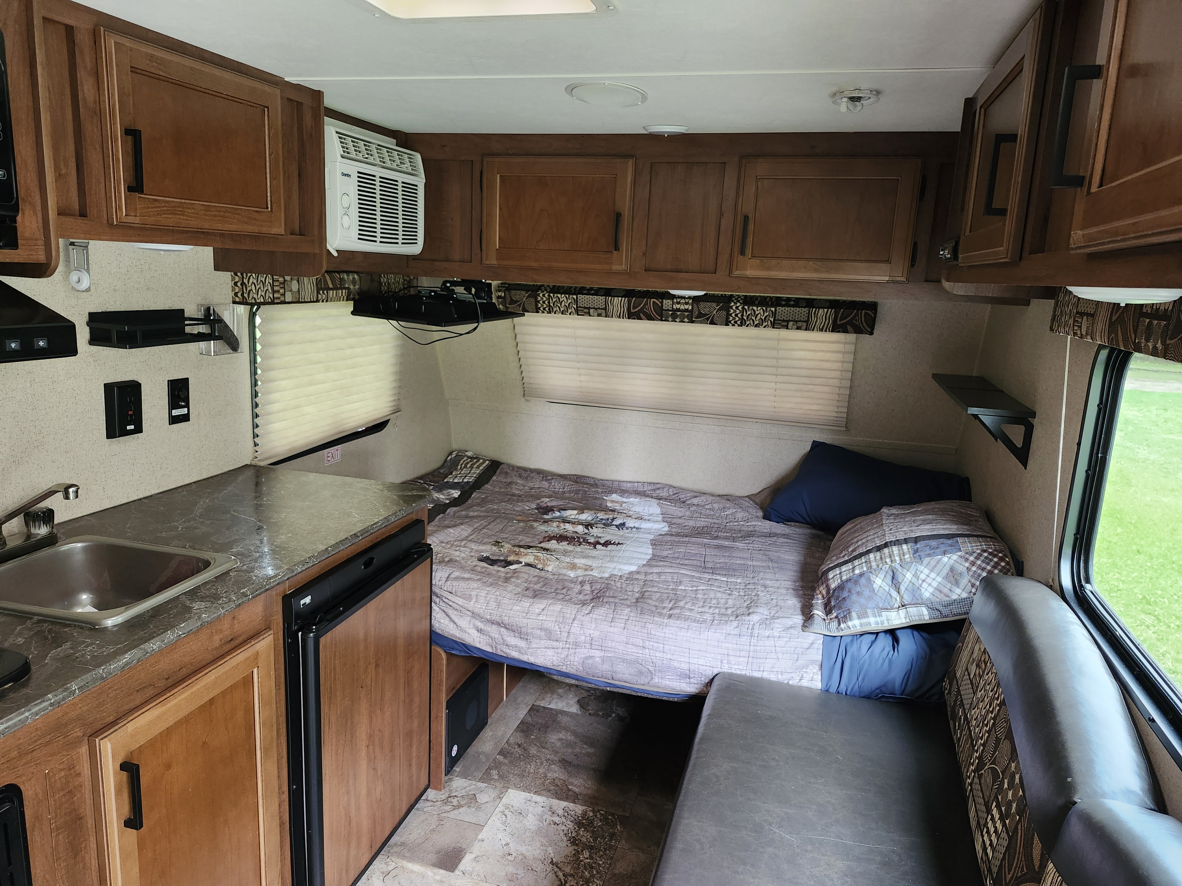 Explore this RV rental's compact interior: kitchen with sink & fridge, cozy bed, AC unit, and functional seating area.. Jayco Jay Flight SLX 2016