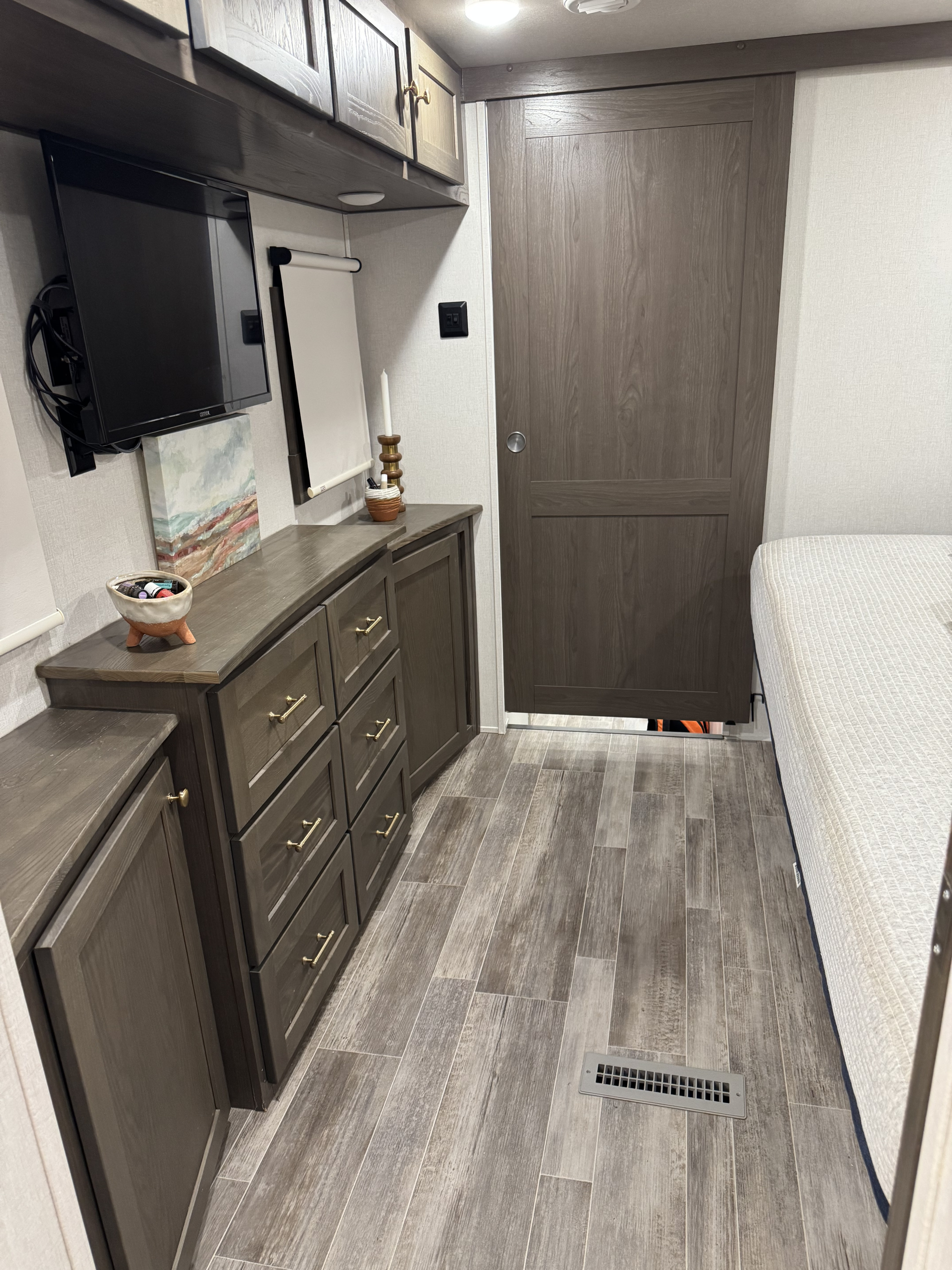 Inside an RV rental: a modern bedroom with wood-look cabinets, TV, and a sliding door to another area.. Forest River Palomino Columbus C 2022