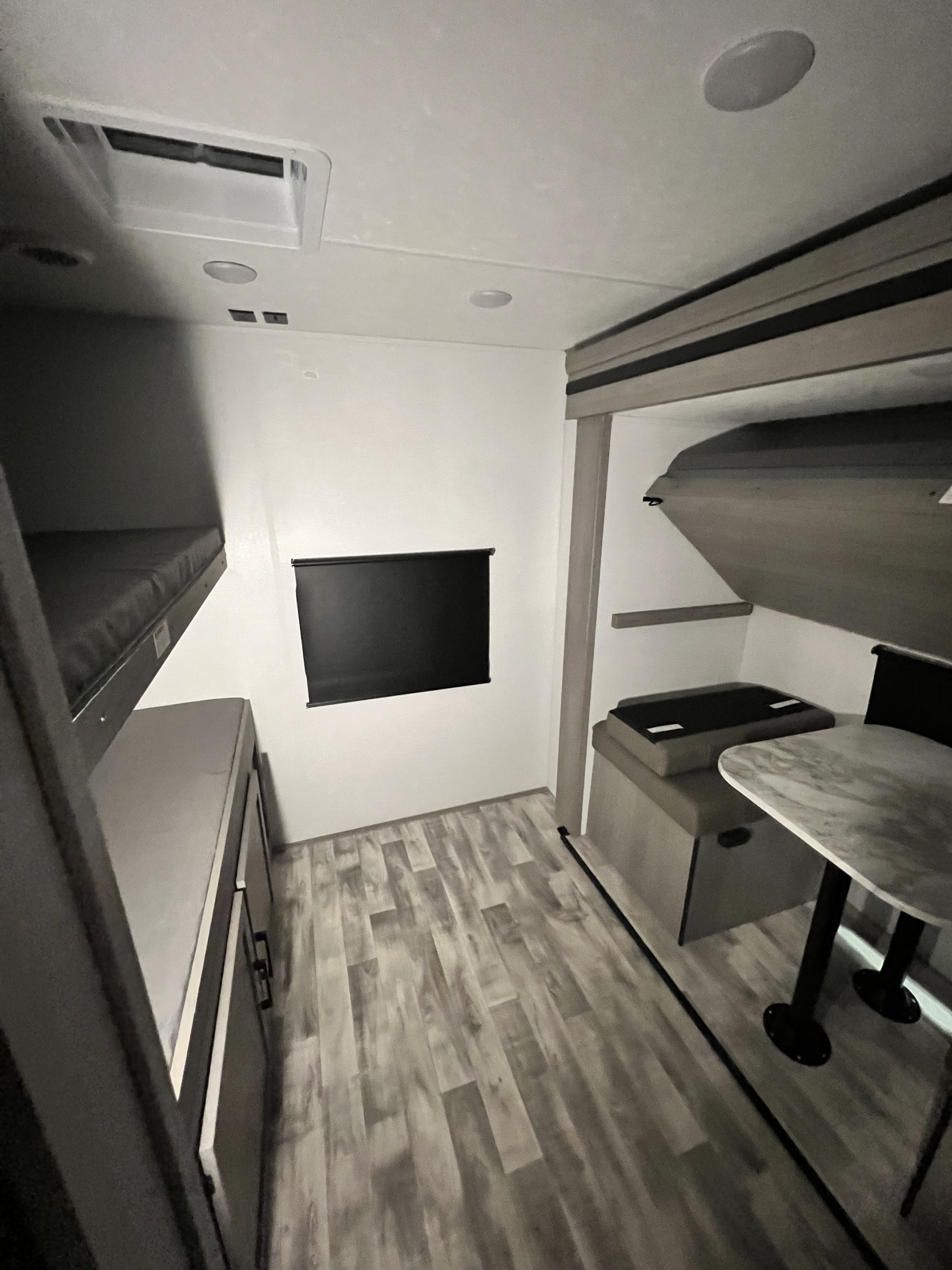 This RV rental bunkhouse room features a modern interior with two bunk beds, a dinette, and light wood-look flooring.. Dutchmen Kodiak Ultimate 2024