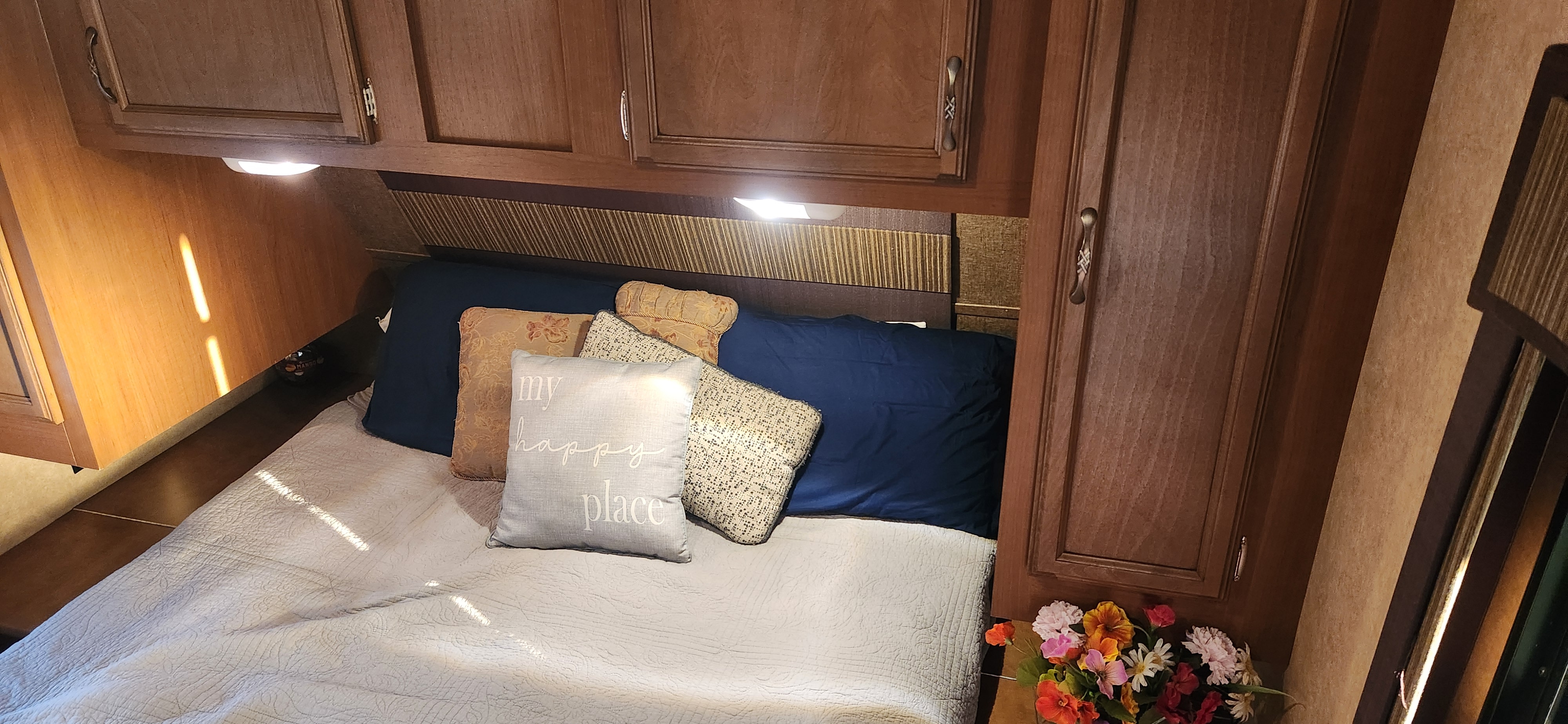 Cozy RV rental bedroom featuring a comfortable bed, overhead cabinets, and decorative pillows, ready for your adventure.. Starcraft Autumn Ridge 2014