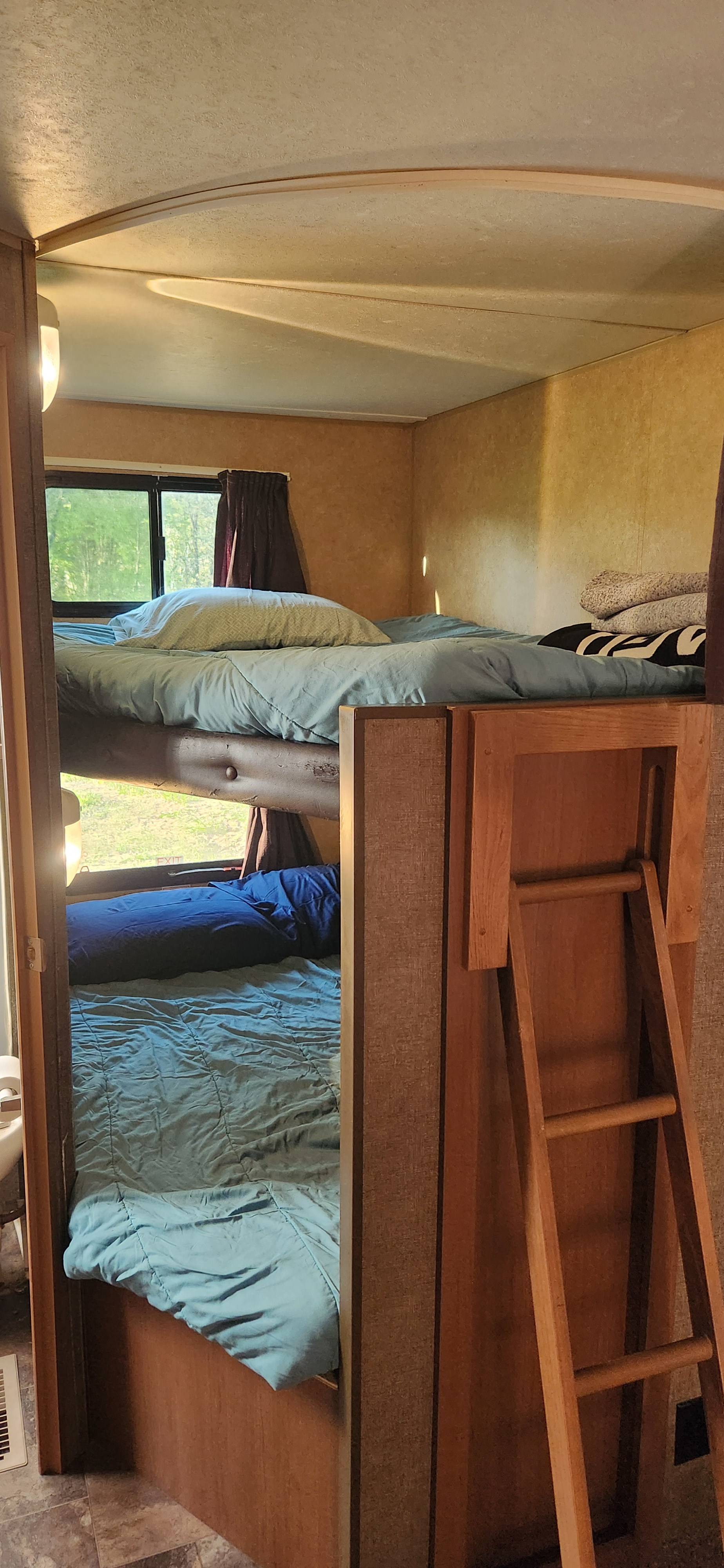 RV rental interior showing cozy bunk beds with light blue bedding and a wooden ladder. Ideal for family camping adventures.. Starcraft Autumn Ridge 2014
