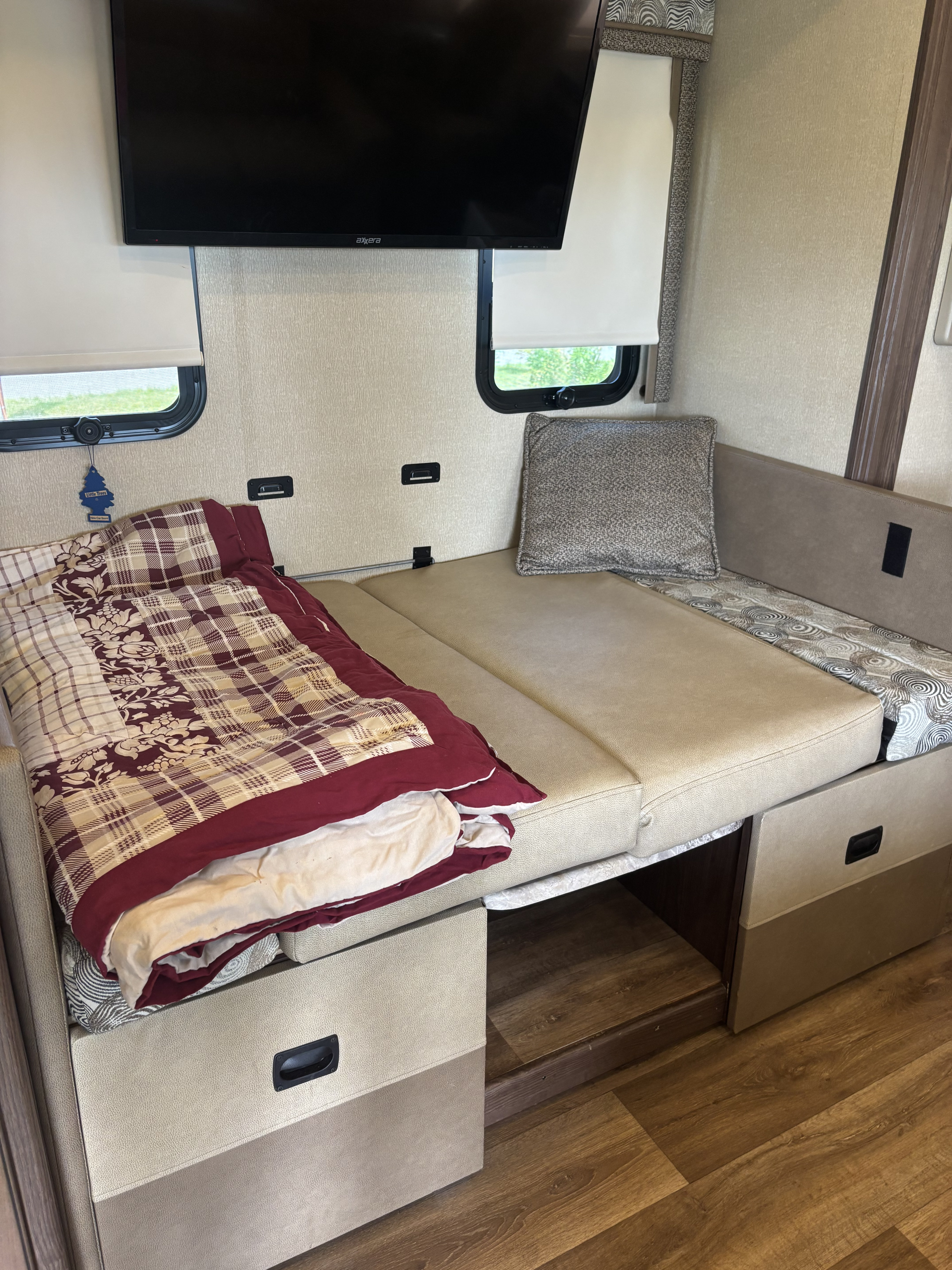 RV rental interior: Dinette converted to a bed with a blanket, mounted TV, and window; shows storage and flooring.. Coachmen pursuit Precision 27ds 2019